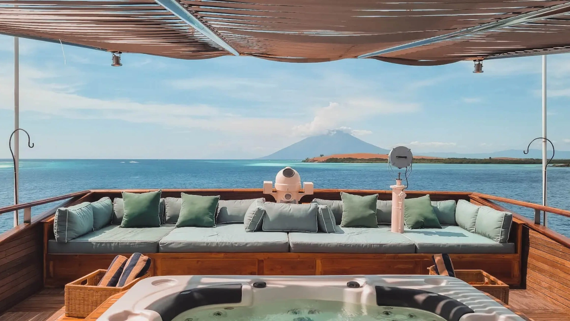 Top-deck jacuzzi and lounge on Kudanil Explorer looking out to a distant volcano