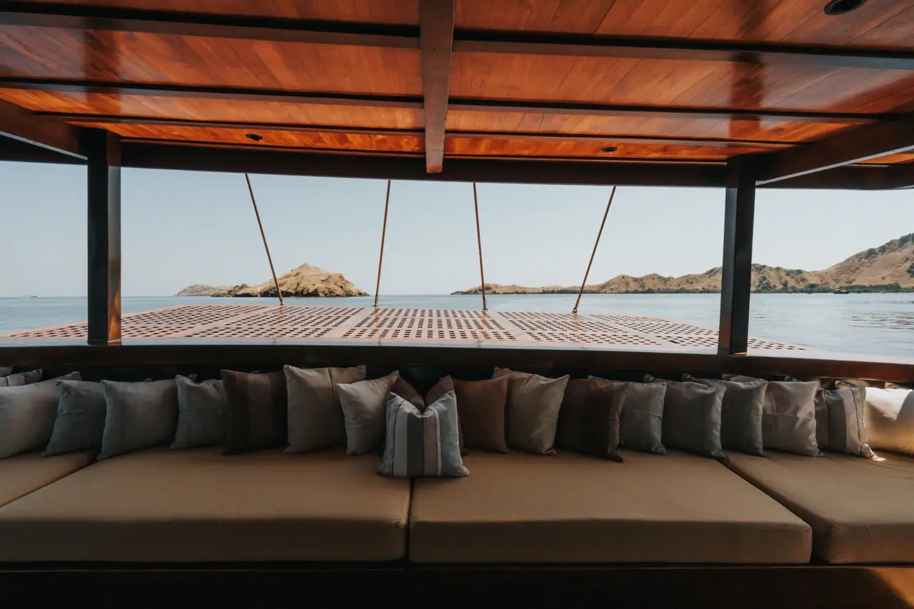 Celestia shaded aft lounge with long banquette and Komodo island view