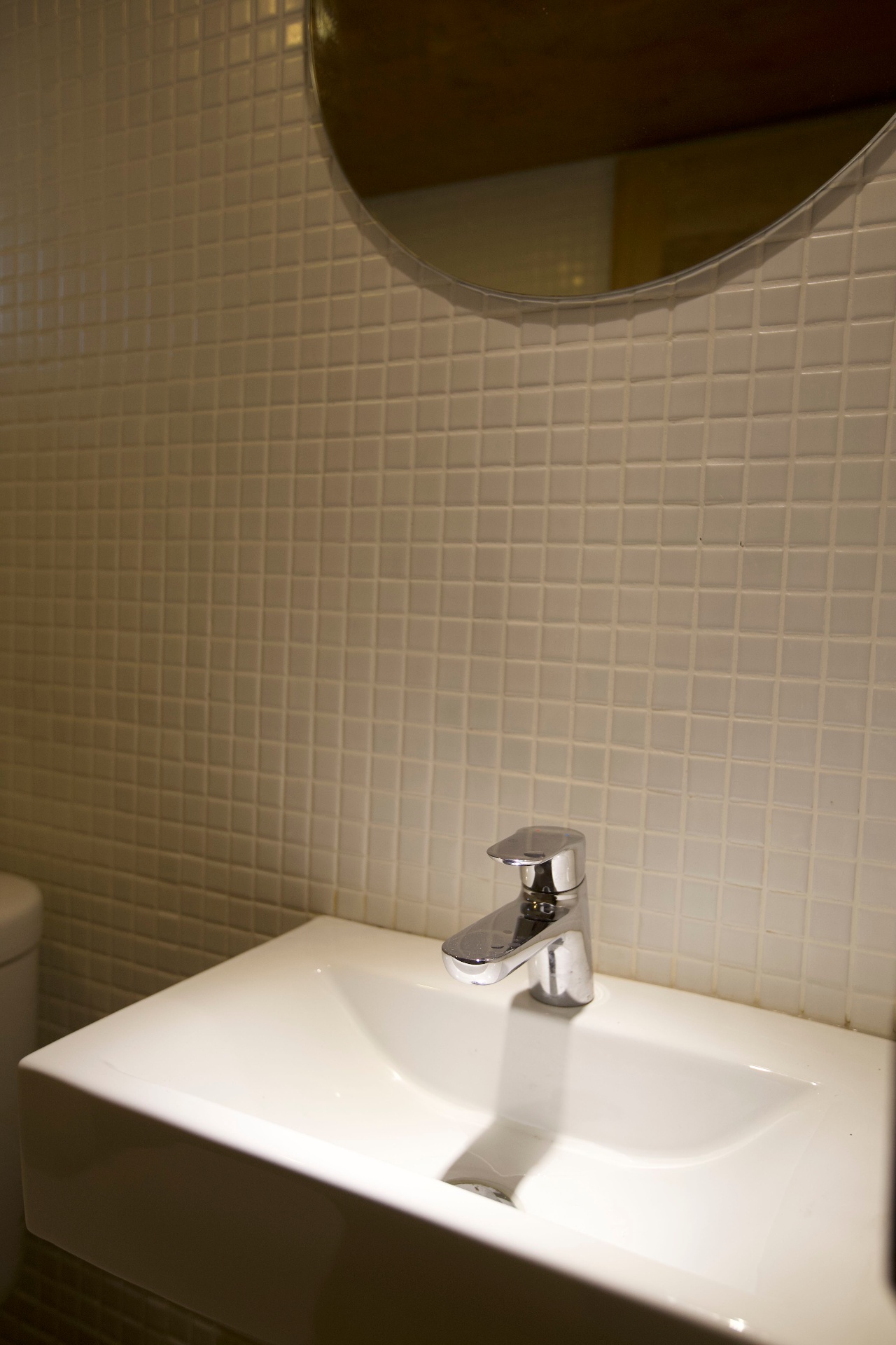 Close-up of chrome mixer tap and white basin against mosaic tile wall on Splendour