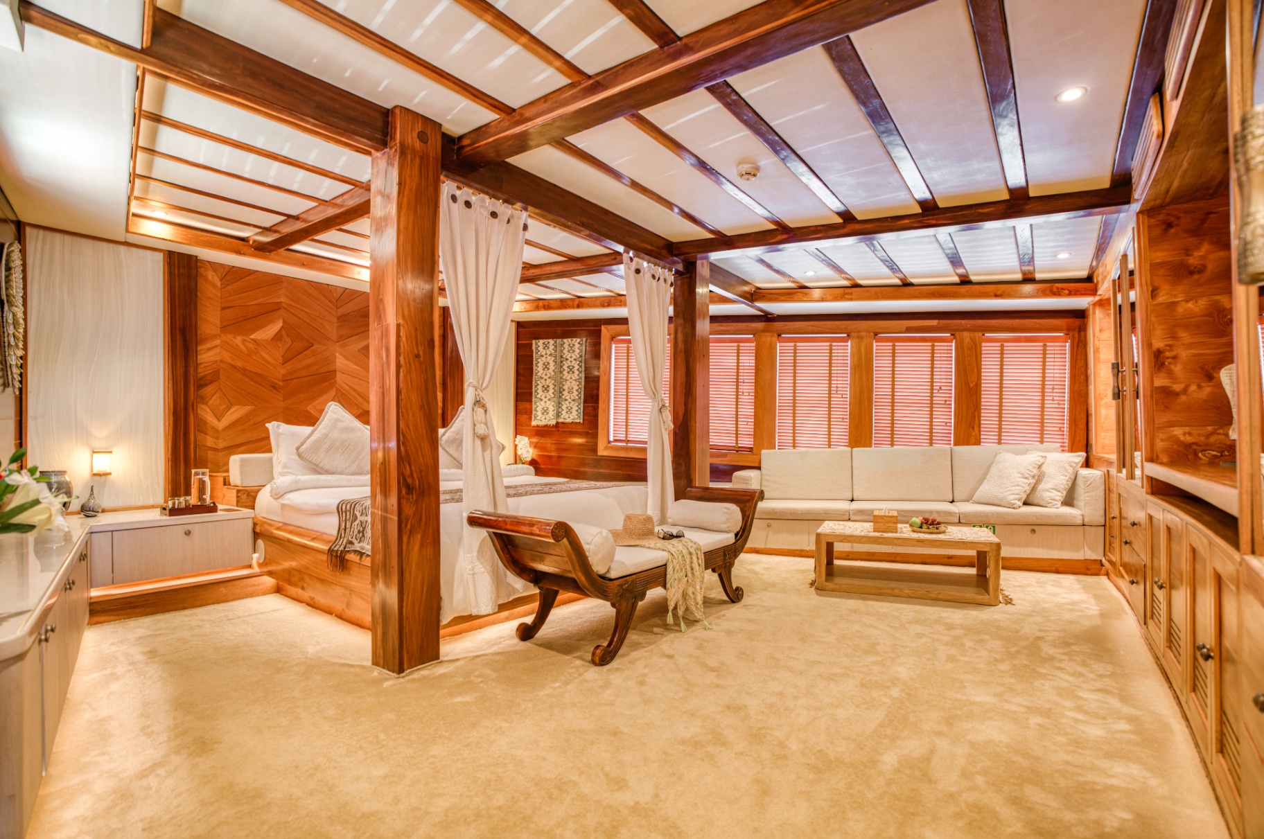 Master suite on Lamima with four-poster king bed, lounge sofa and teak paneling