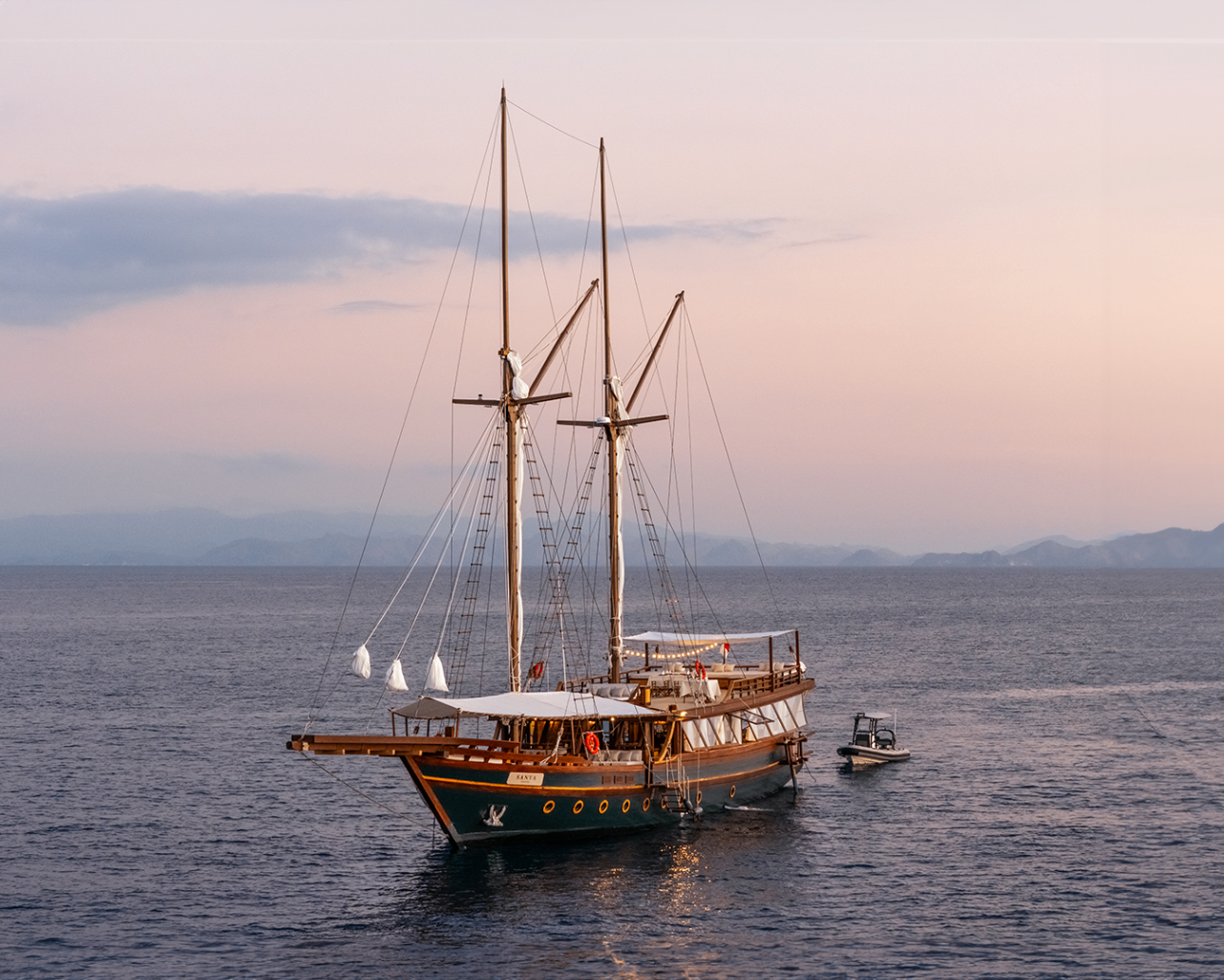 Sanya lit softly at dusk while anchored on calm sea with pastel sky behind