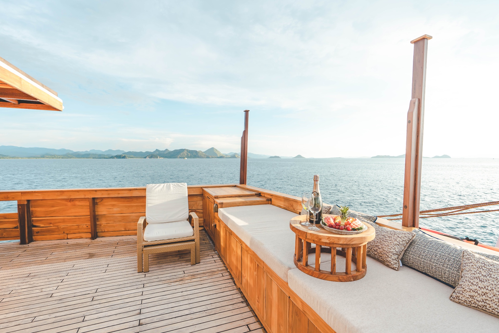 Mischief bow daybed with champagne, fruit platter and teak side table facing the Flores Sea