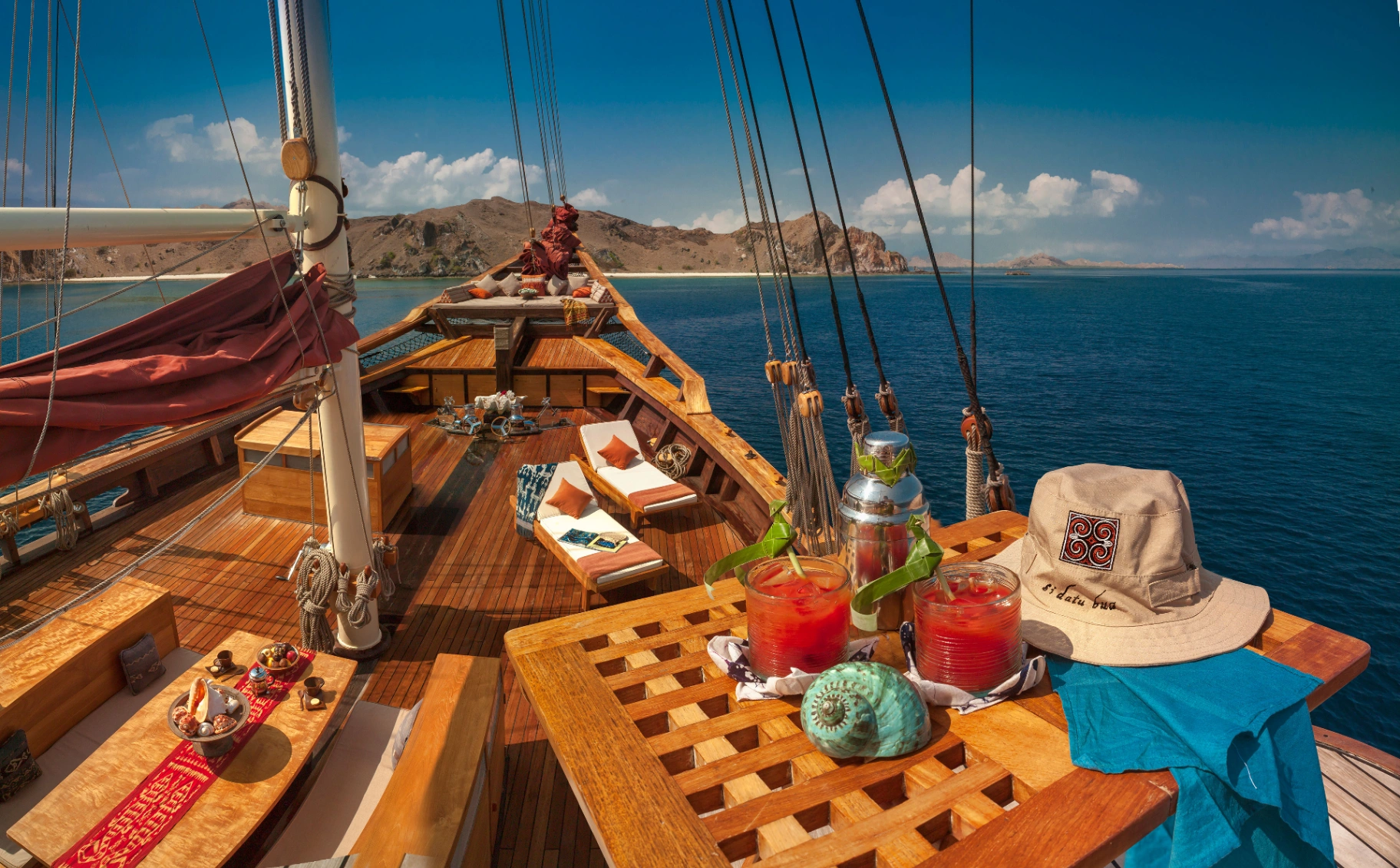 Foredeck of Si Datu Bua with sun loungers and cocktails on a bright Komodo day