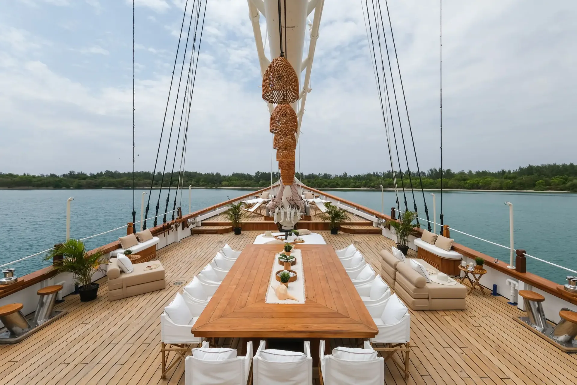 Mutiara Laut foredeck dining table with the bow pointing toward a mangrove shore