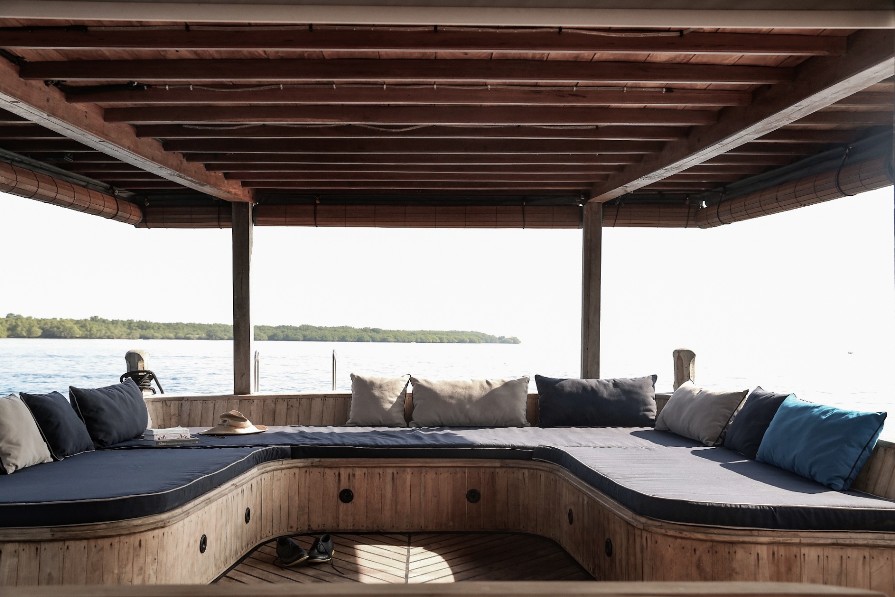 Splendour covered deck lounge with wraparound sofa, navy cushions and sea views over mangroves