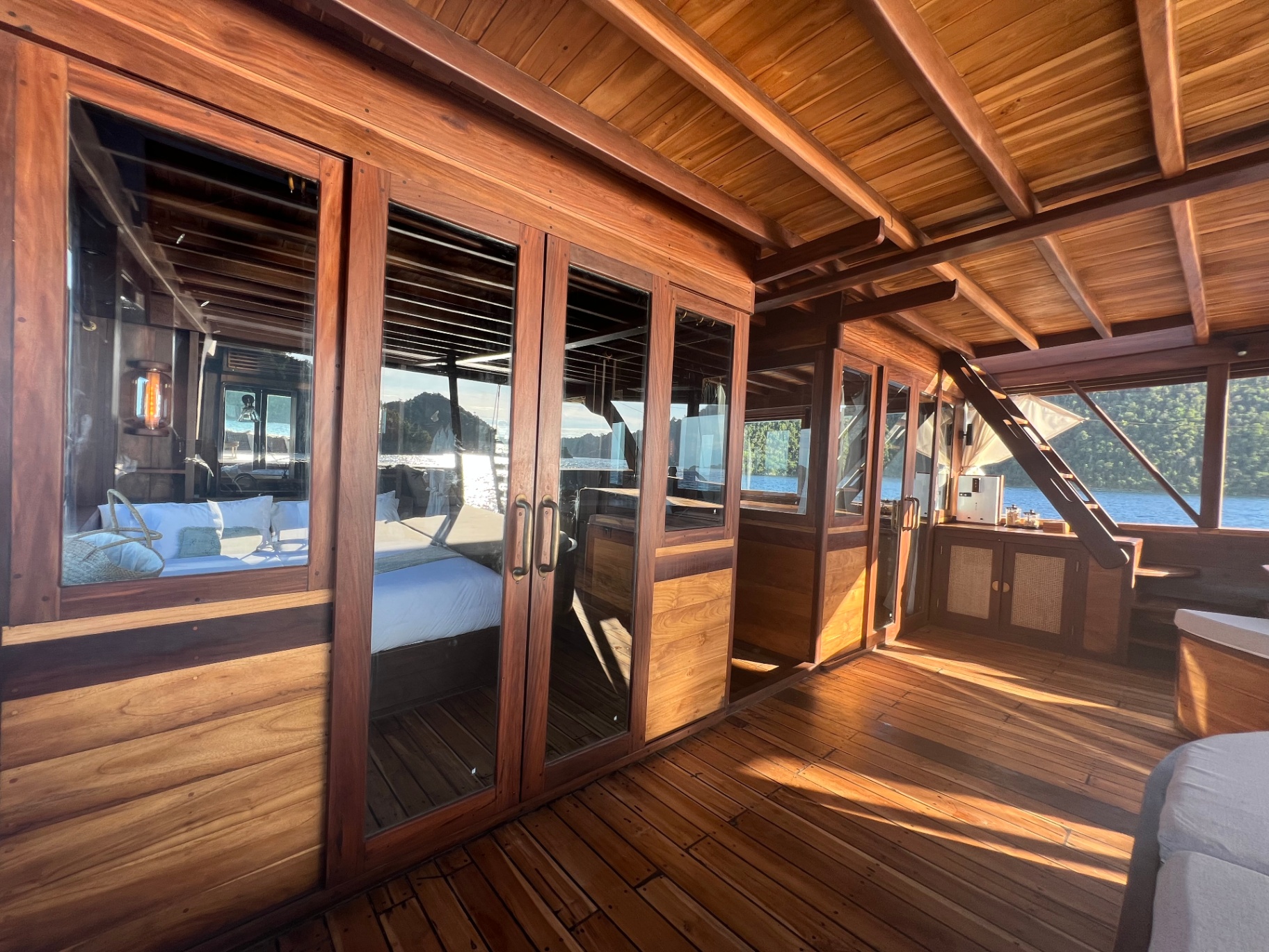 Warm daylight on Dewata's chill deck passage with glass doors into the master cabin