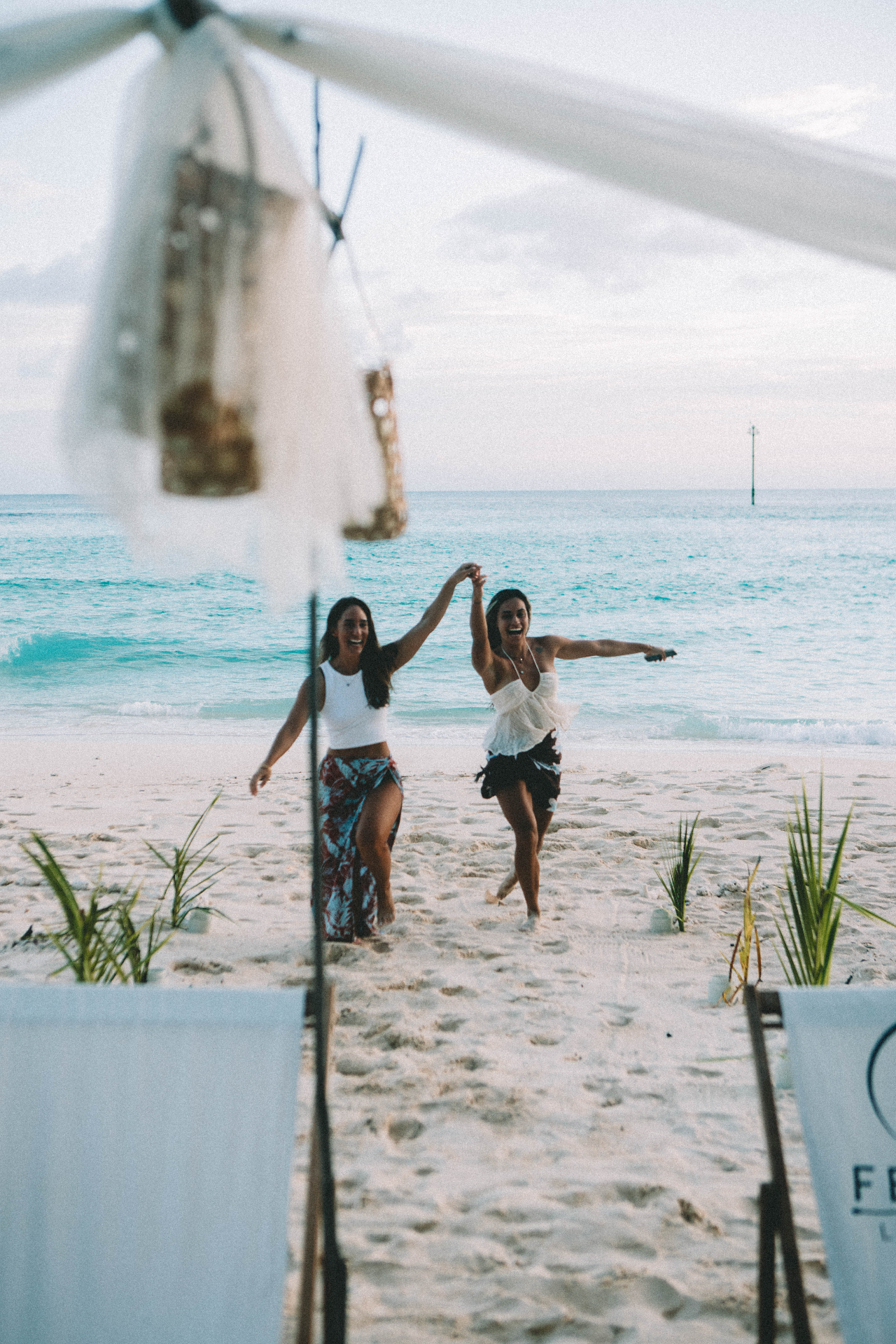 Fenides guests running onto a white-sand beach picnic setup