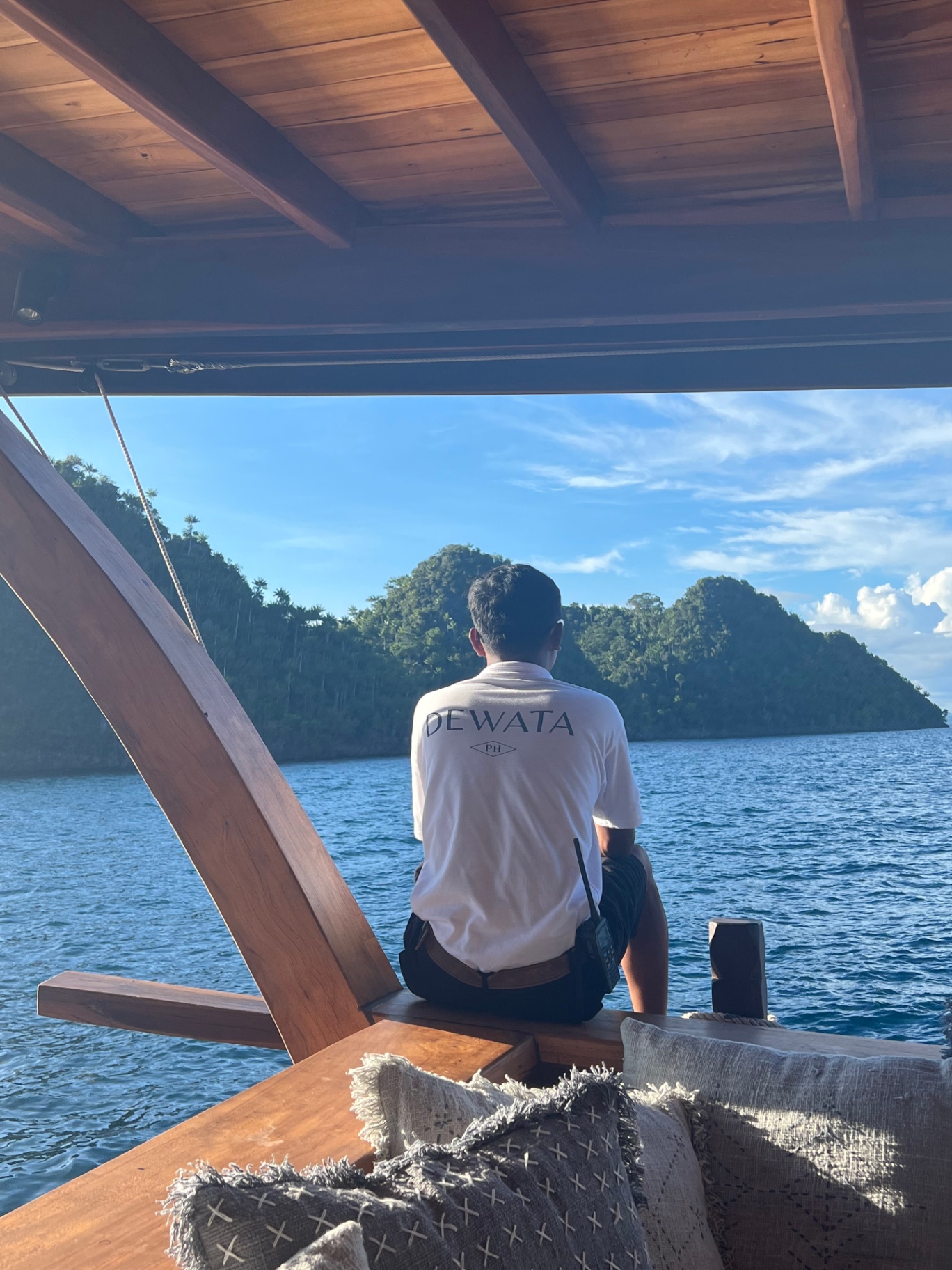 Dewata crew member on the aft deck watching over a Raja Ampat cove