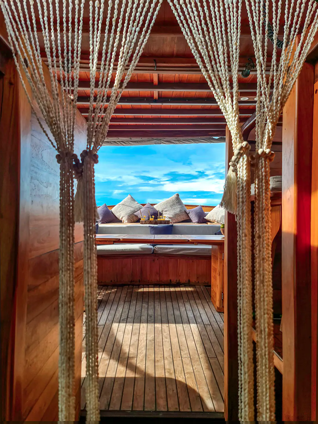 Shell bead curtain framing the aft deck daybed and sky on Anne Bonny