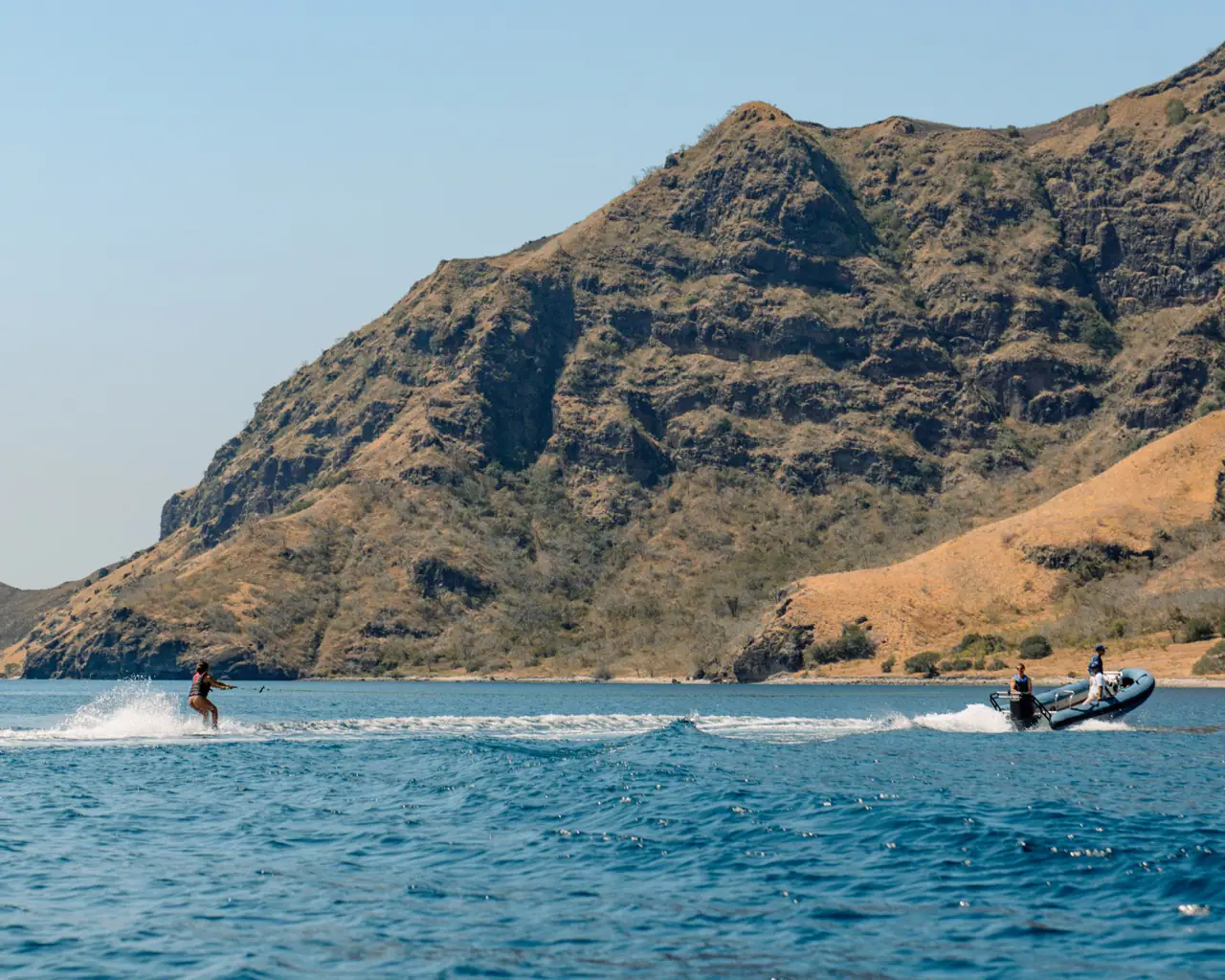 Wakeboarding behind Celestia's tender against dry island cliffs