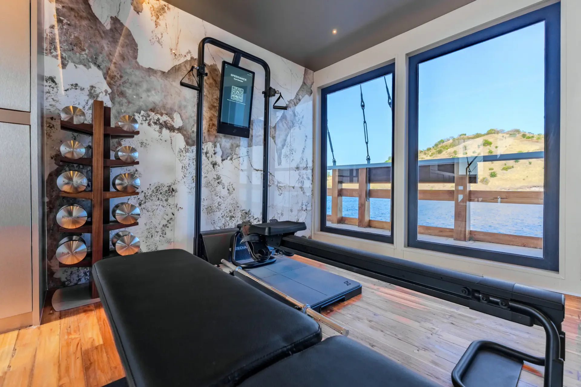Kayra gym with Speediance smart trainer, dumbbells and Komodo-view windows