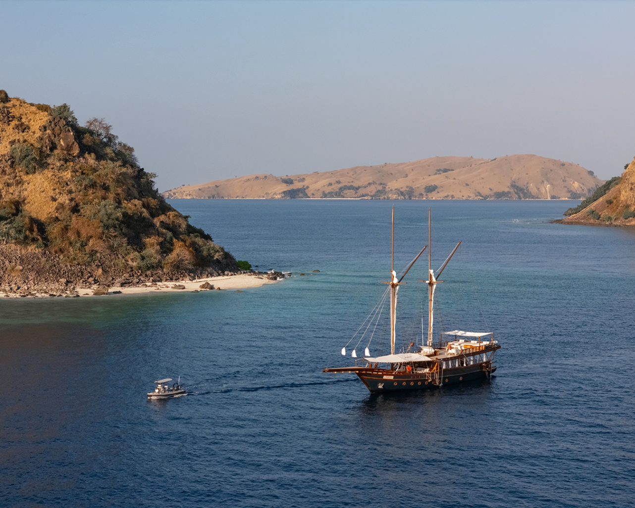 Sanya anchored between Komodo islands with a tender approaching across calm water