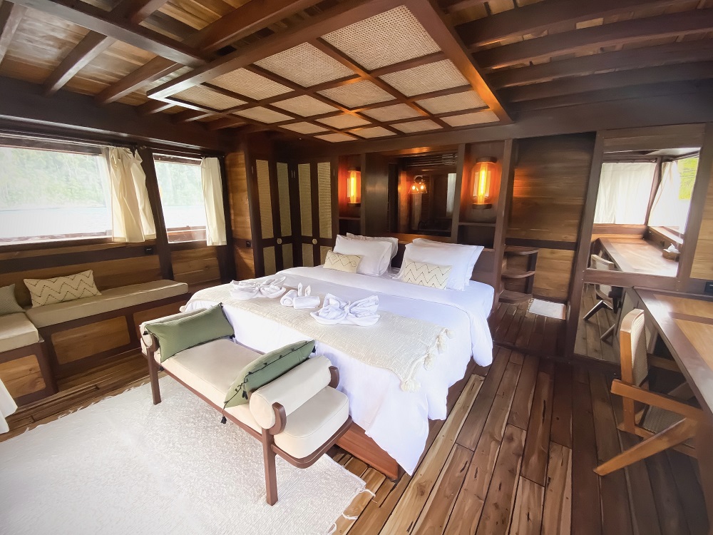 Master cabin on Senja with king bed, woven ceiling panels and windows over the water