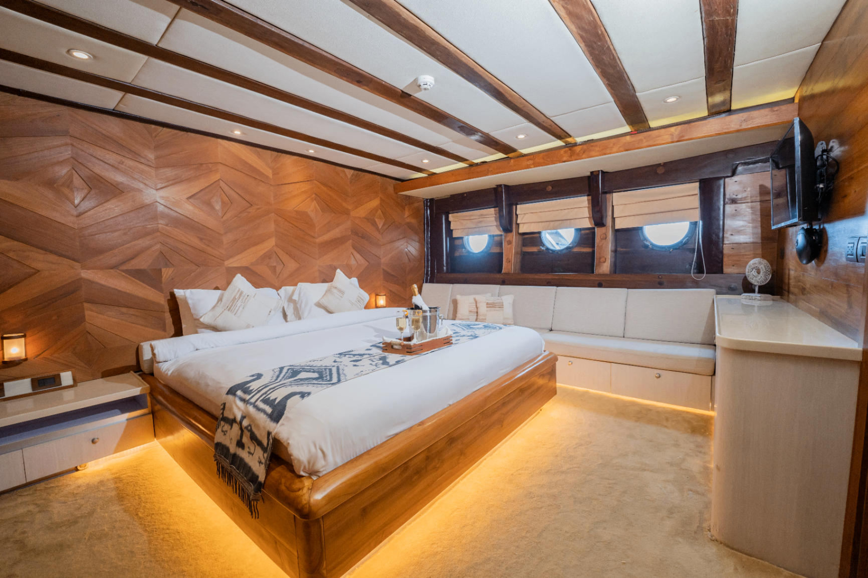 Dolphin cabin on Lamima with king bed, three porthole windows and lounge banquette