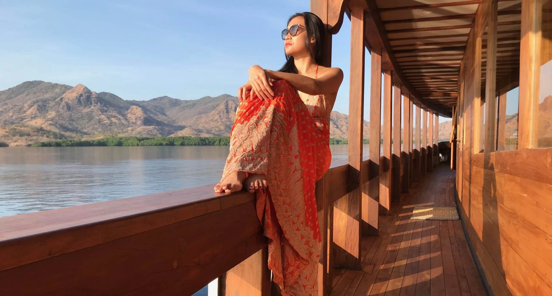 Guest in a sarong relaxing on the teak deck of Prana by Atzaró at golden hour