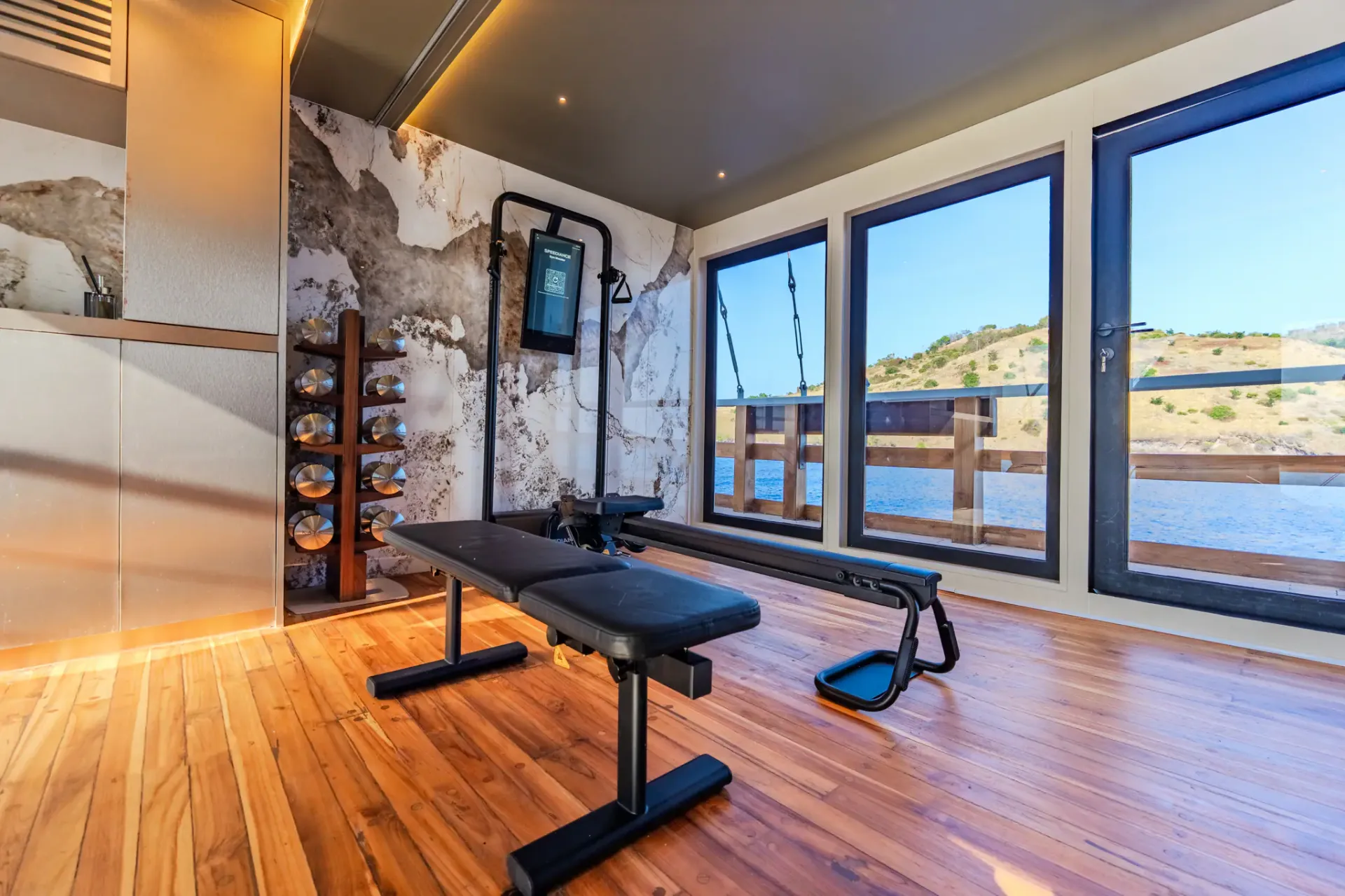 Gym bench and free weights on Kayra facing large windows over the sea