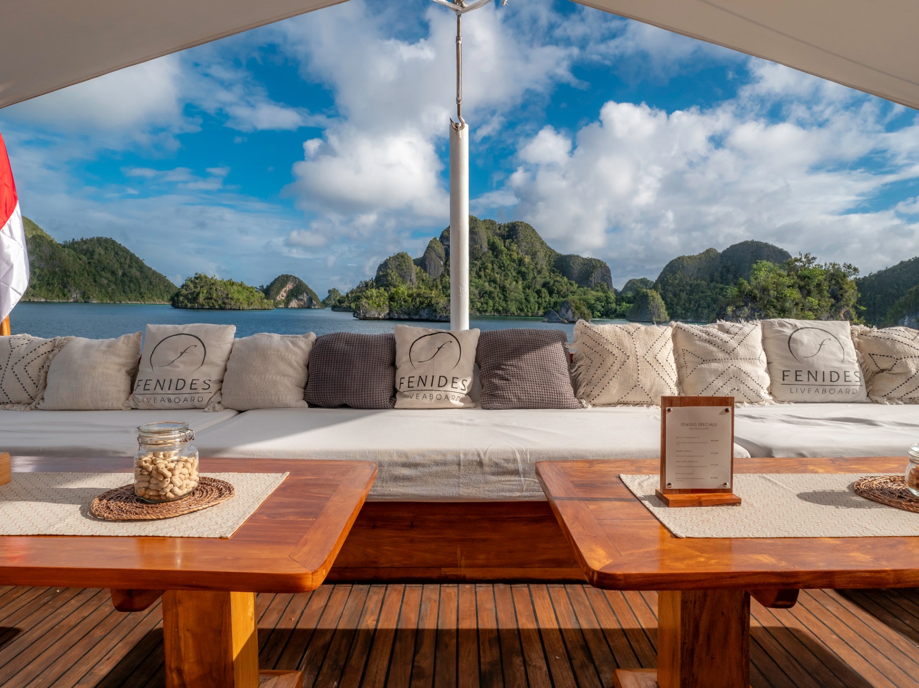Fenides foredeck lounge with logo cushions overlooking Raja Ampat karst islands