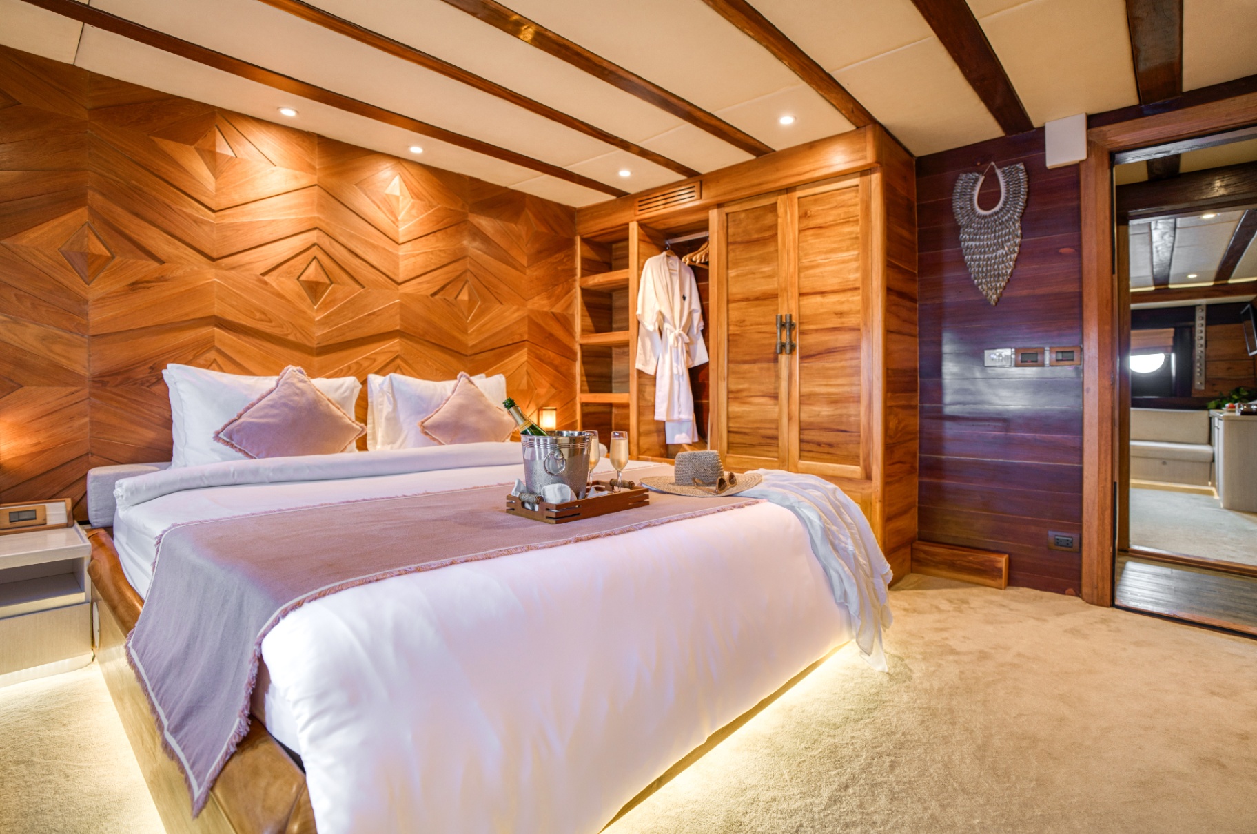 Guest cabin on Lamima with king bed, champagne welcome tray and carved teak wardrobe