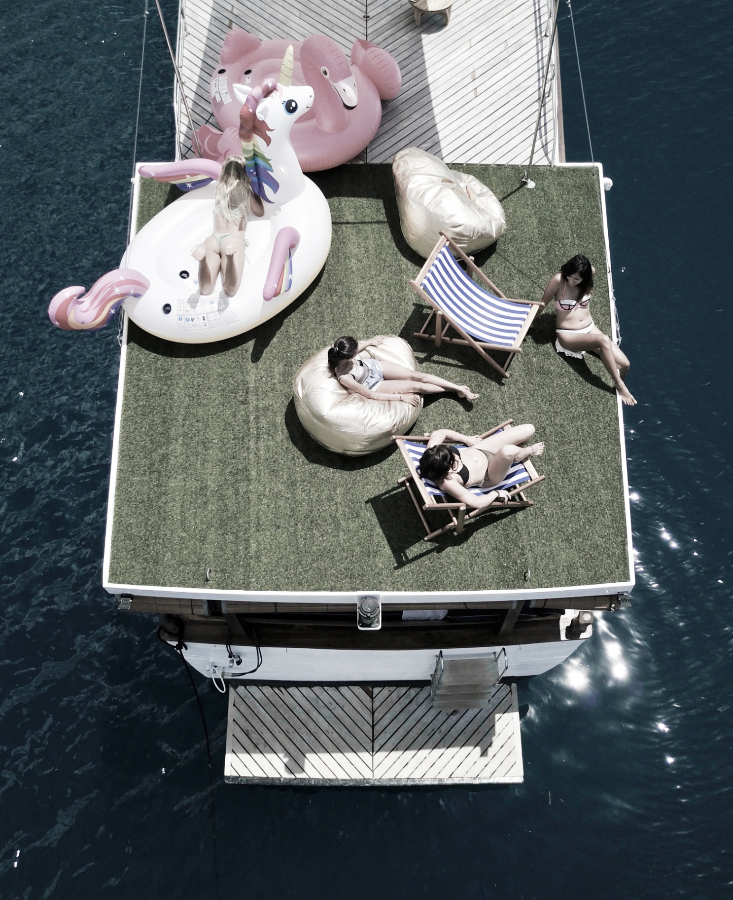 Guests relaxing on Splendour's sundeck with bean bags, deck chairs and inflatable unicorn and flamingo floats