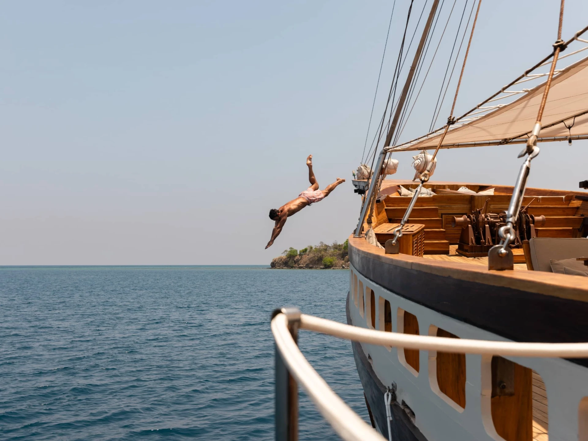 Guest diving off the bow of Prana by Atzaró into the Indonesian sea