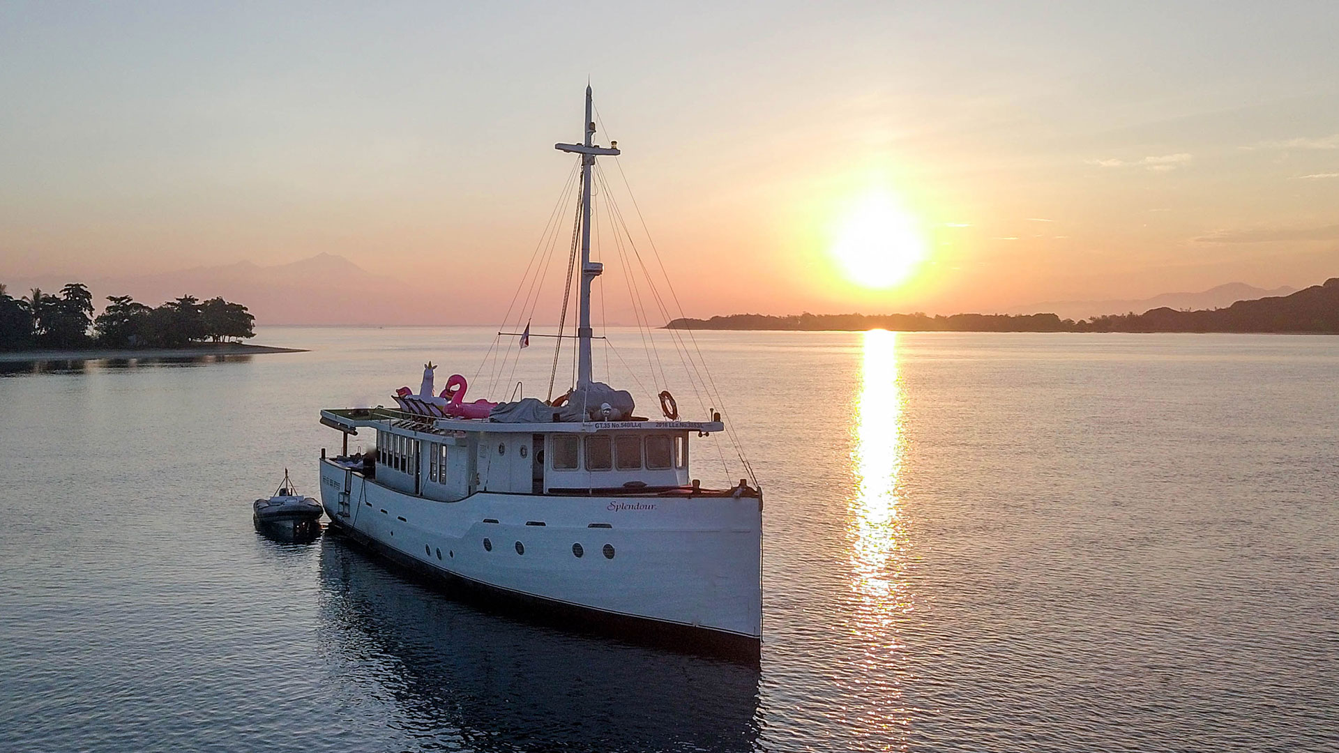 Splendour at sunset on calm water with inflatable floats on the upper deck and the sun low on the horizon
