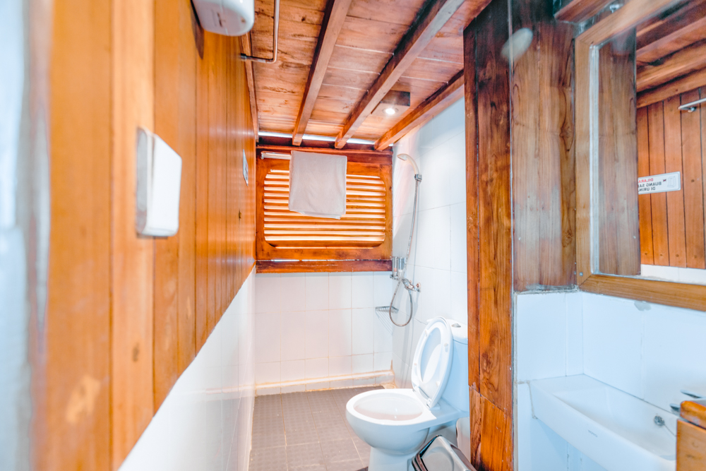 Bathroom on Adishree with teak-and-white tiled walls, walk-in shower and folded towel