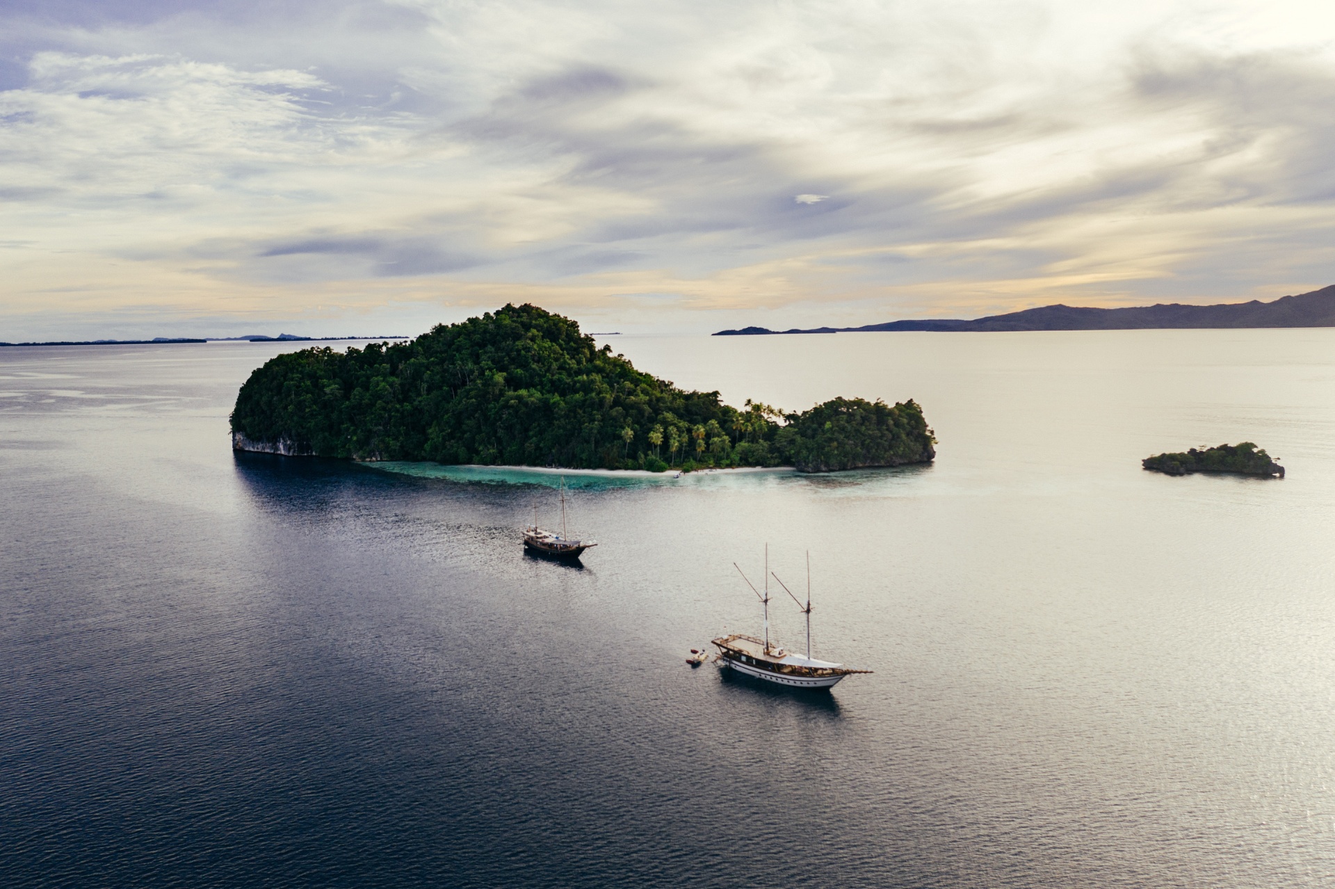 Aerial view of Senja and a second phinisi anchored off a green Raja Ampat island