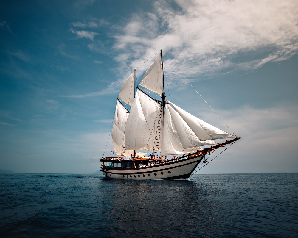 Senja under full white sails on deep blue water beneath a bright blue sky
