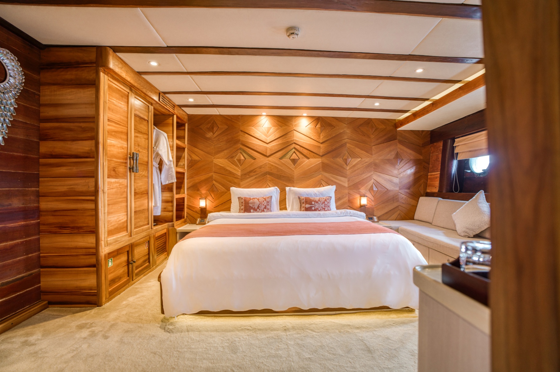Guest cabin on Lamima with king bed, diamond-inlay teak headboard wall and lounge sofa