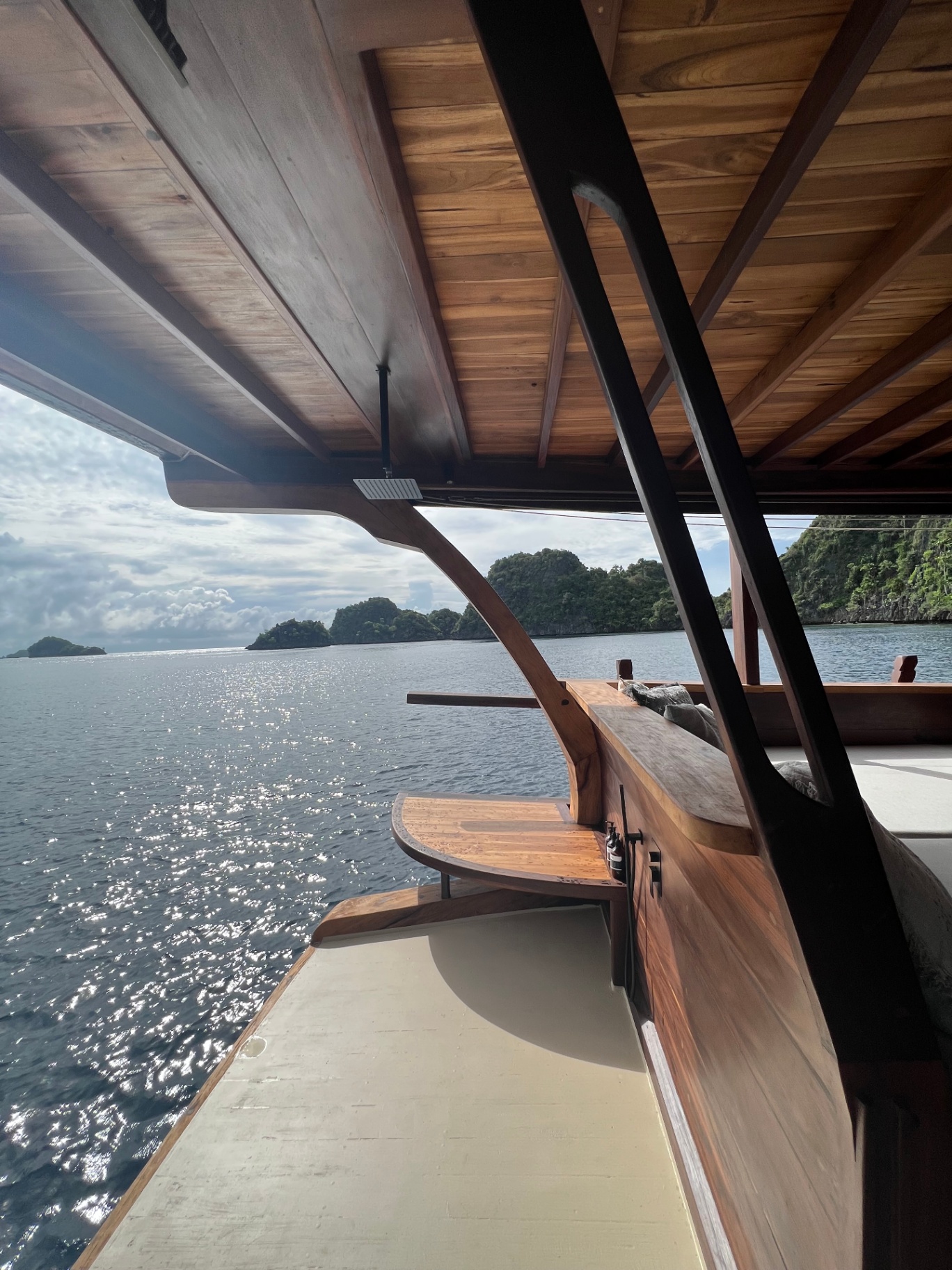 Dewata back terrace with teak deck opening onto sparkling Raja Ampat water