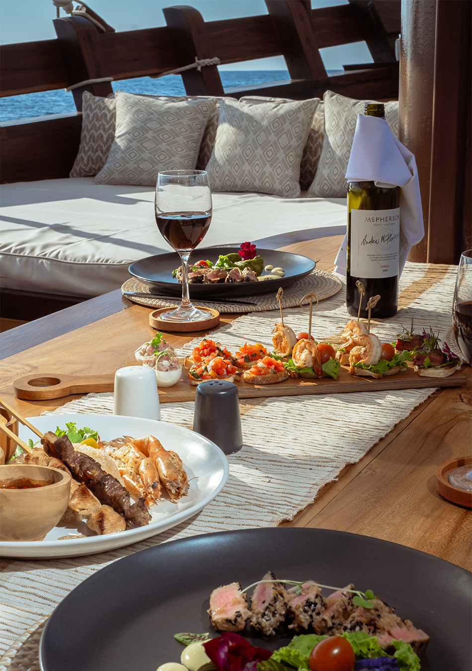 Elegant lunch spread with wine and plated dishes on Sanya's teak dining table