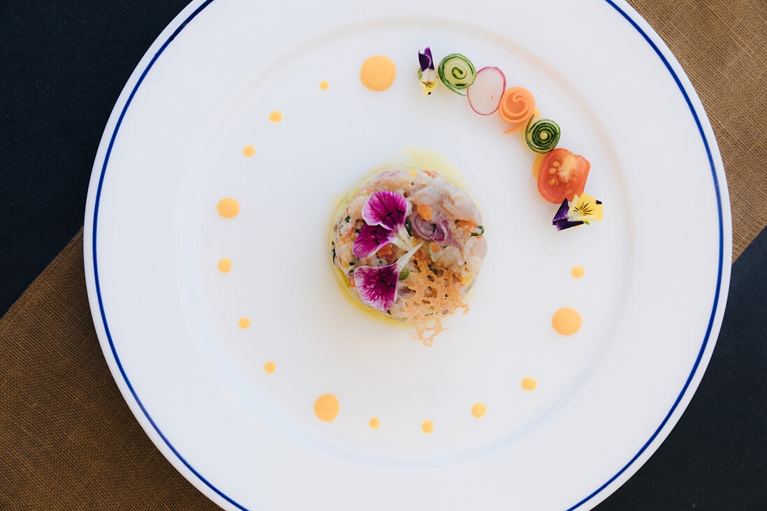 Plated ceviche with edible flowers and vegetable garnish on Kudanil Explorer