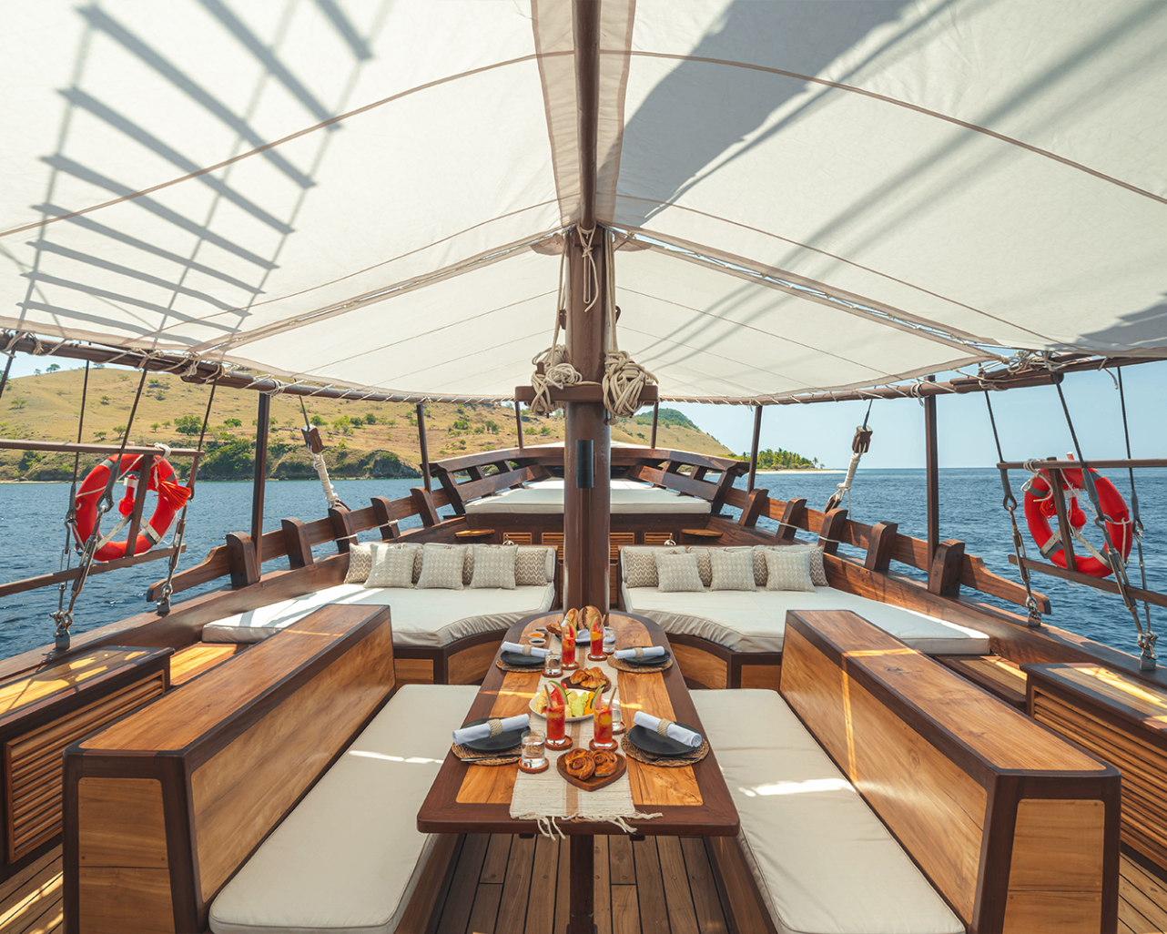 Symmetrical foredeck table setting on Sanya with breakfast pastries and tropical drinks