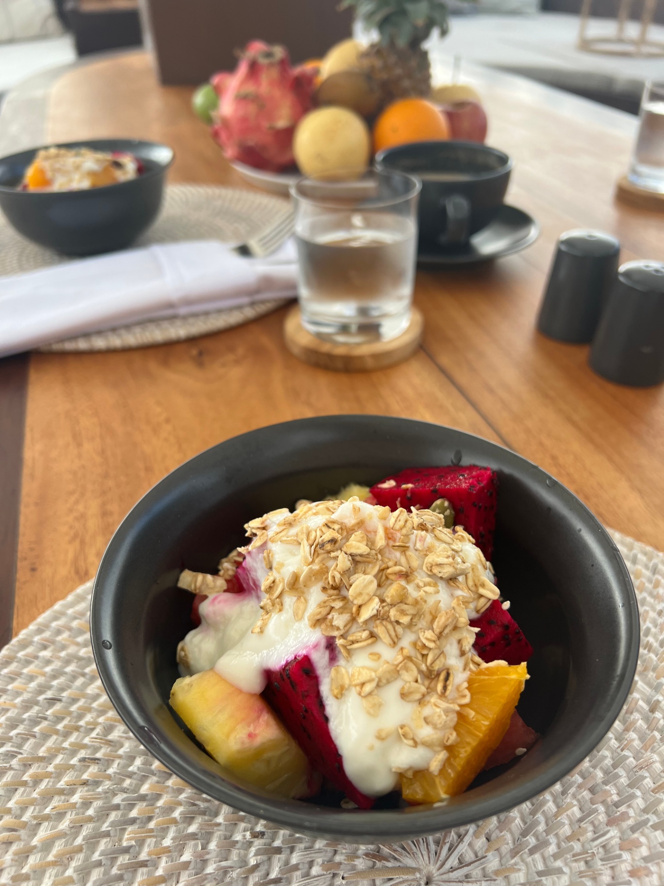 Breakfast fruit bowl with yogurt and granola on Dewata's dining table with tropical fruit platter