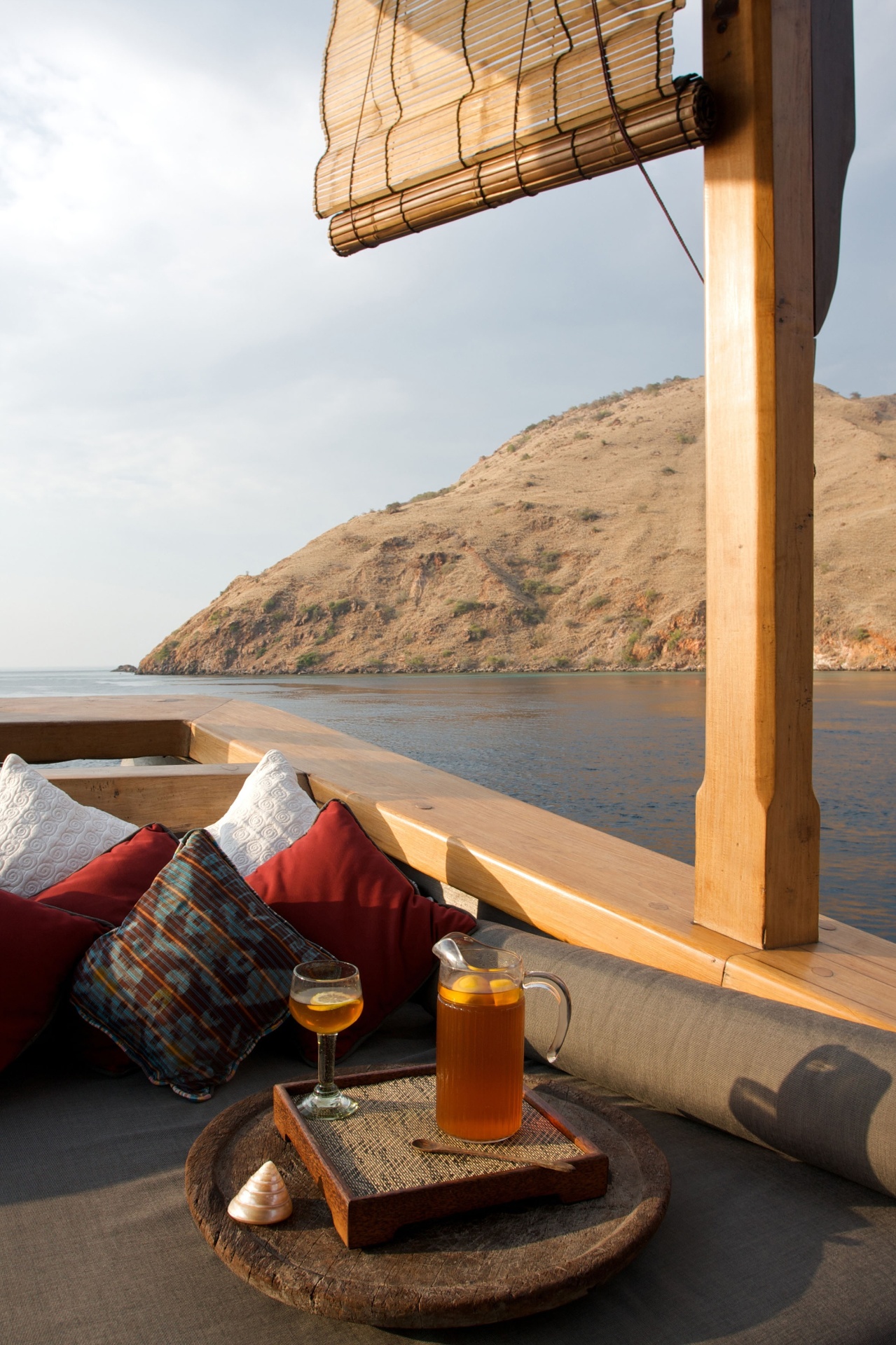 Iced tea and ikat cushions on Silolona's deck with a Komodo hillside behind