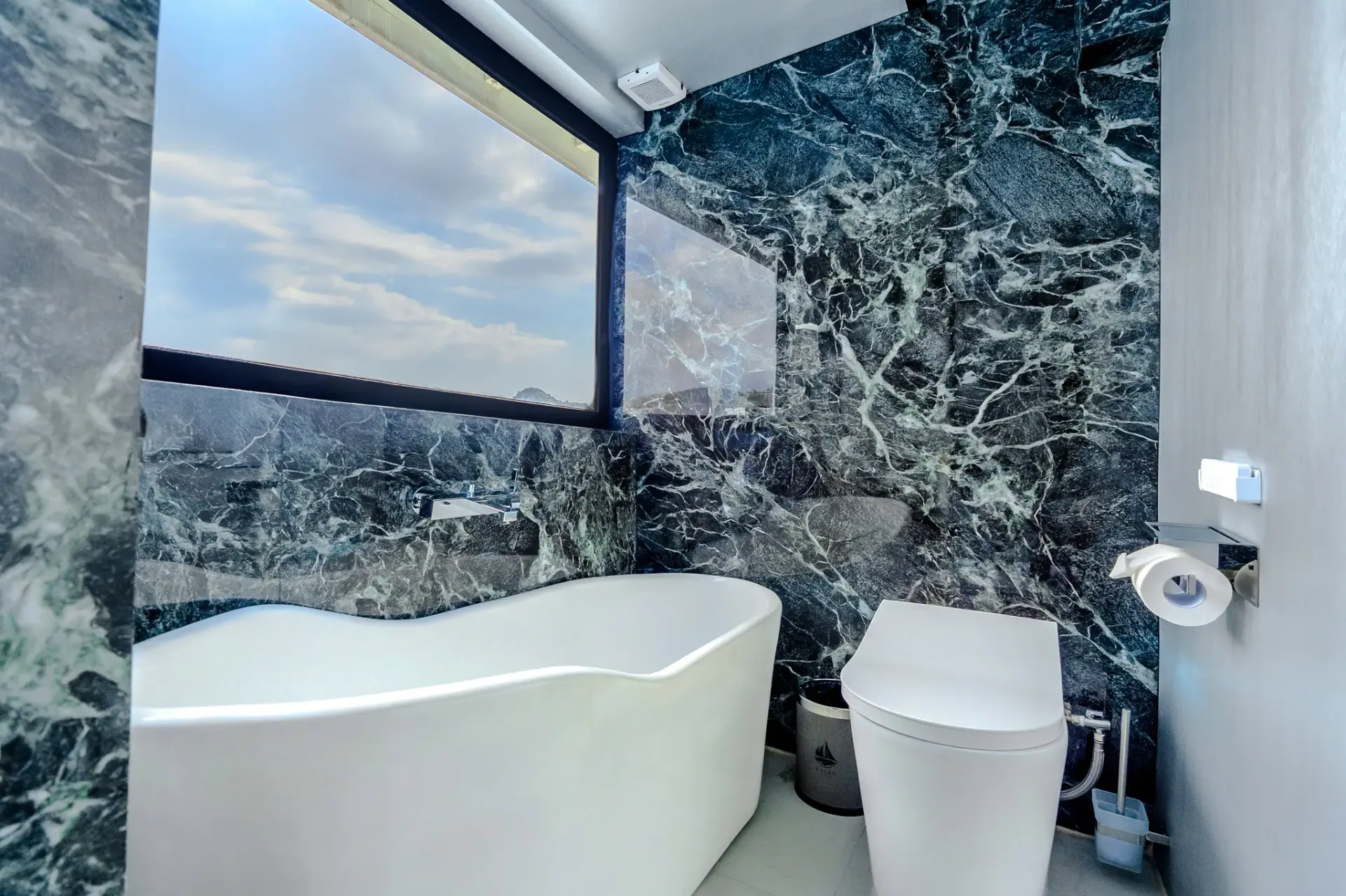 Freestanding tub in Kayra master bathroom against dramatic green marble