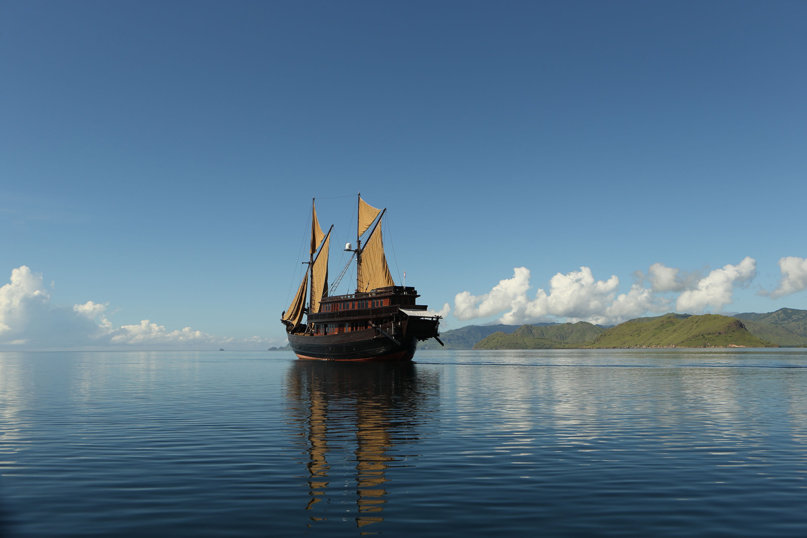 Alila Purnama on mirror-calm sea with distant Raja Ampat islands