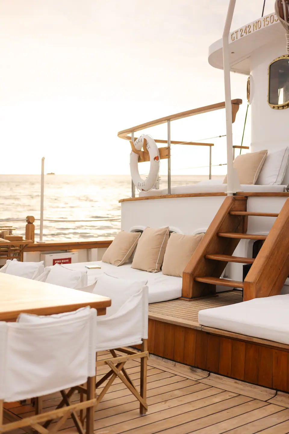 Mutiara Laut aft deck at sunset with cushioned banquette and teak steps