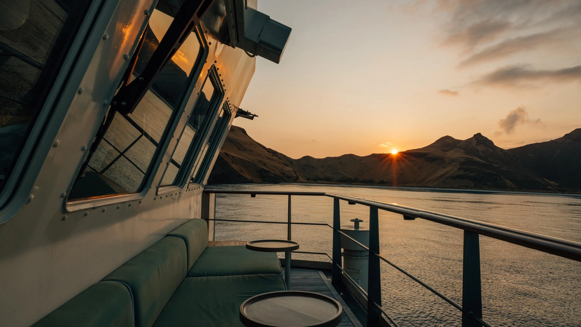 Side deck banquette outside the wheelhouse at sunset over Komodo hills