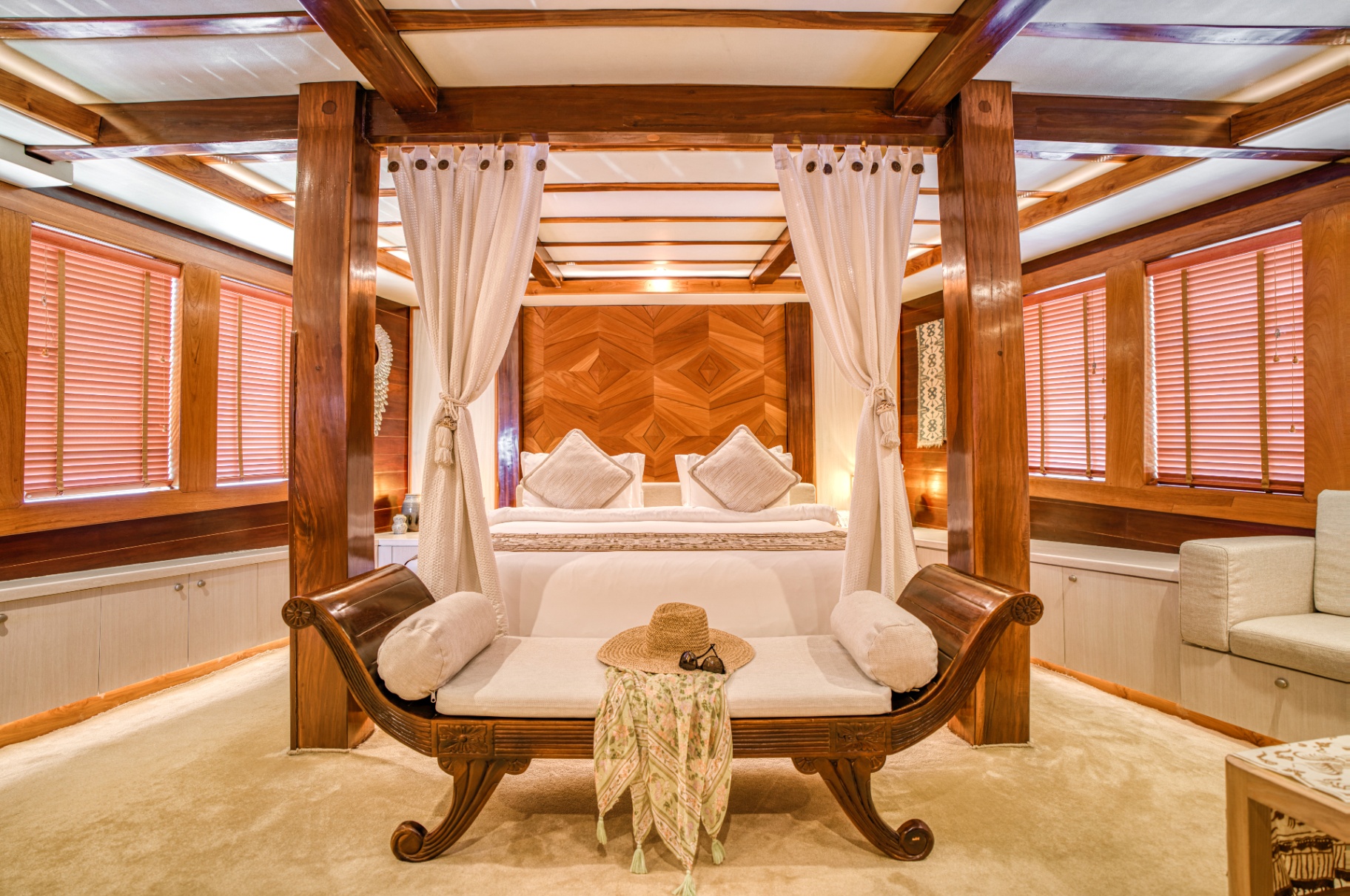 Four-poster canopy bed in Lamima's master suite framed by carved teak columns and louvred shutters