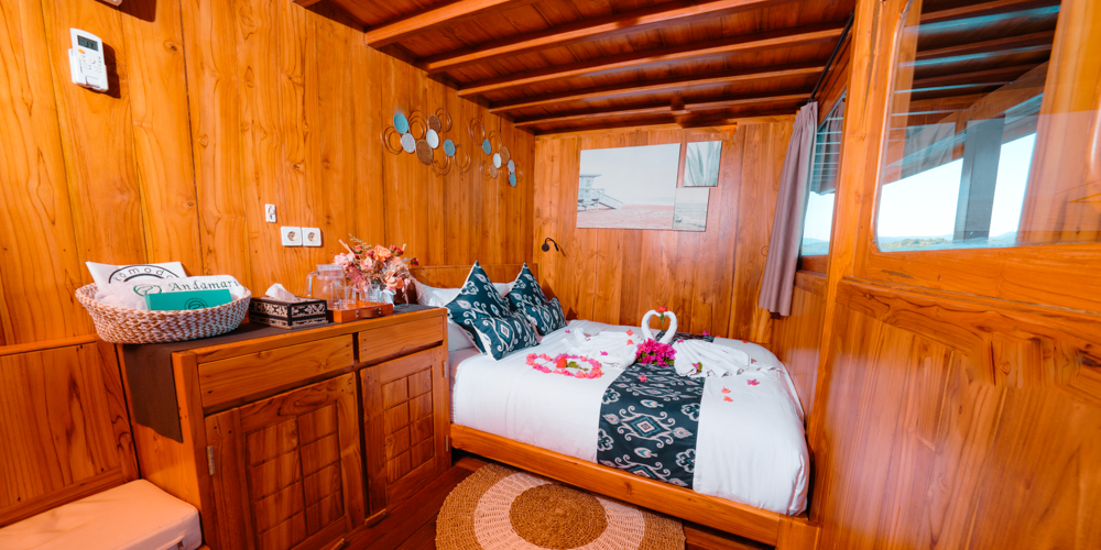 Andamari guest cabin with a double bed, decorative cushions, wood cabinetry and round woven rug