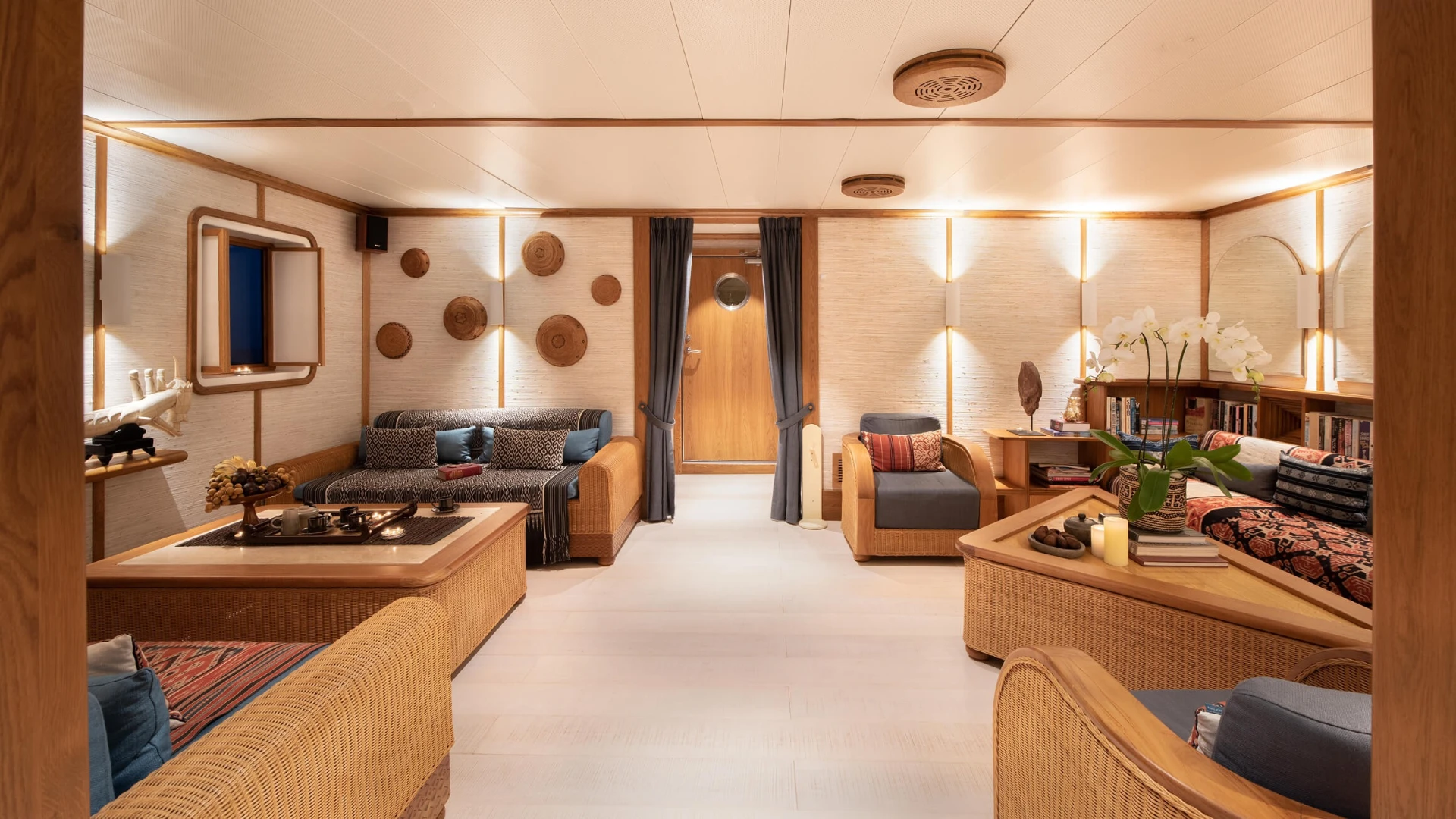 Library lounge on Kudanil Explorer with rattan sofas, ikat cushions and bookshelves
