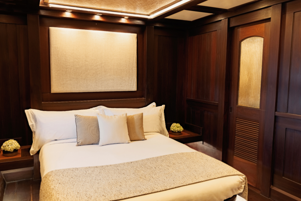 Cabin aboard Dunia Baru with king bed, teak panelling and soft cove lighting
