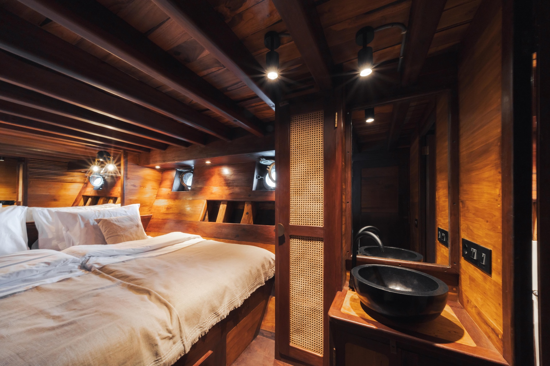 Deluxe cabin on Nataraja seen from the vanity with black stone basin and porthole windows over the bed