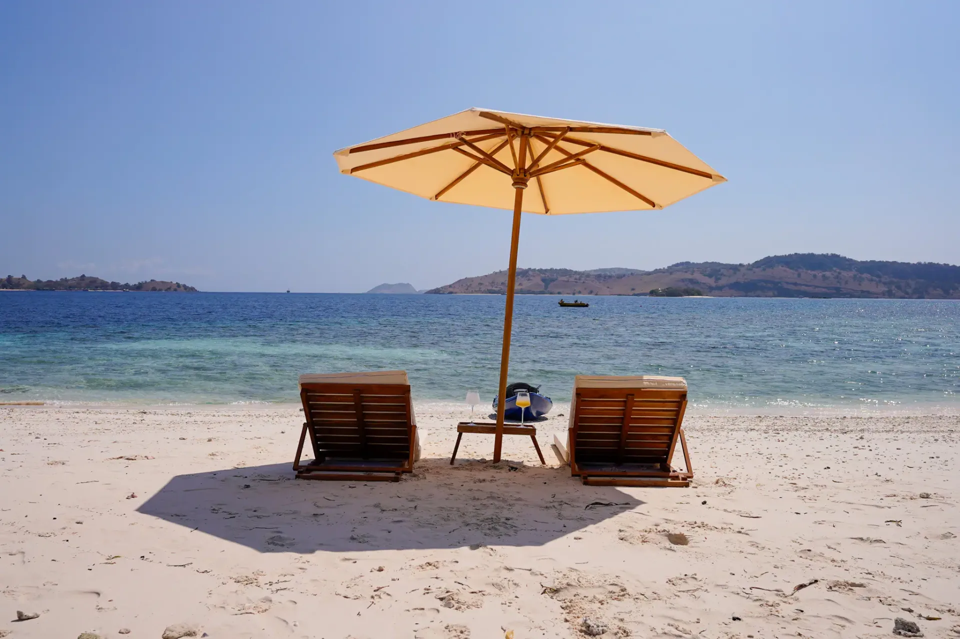Beach setup from Kayra Phinisi with two loungers and parasol on white sand