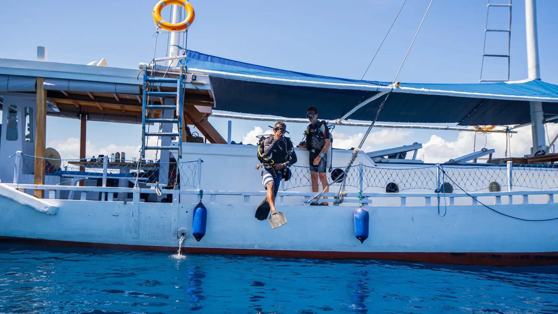 Scuba diver giant-striding off Jinggo Janggo's deck in full gear