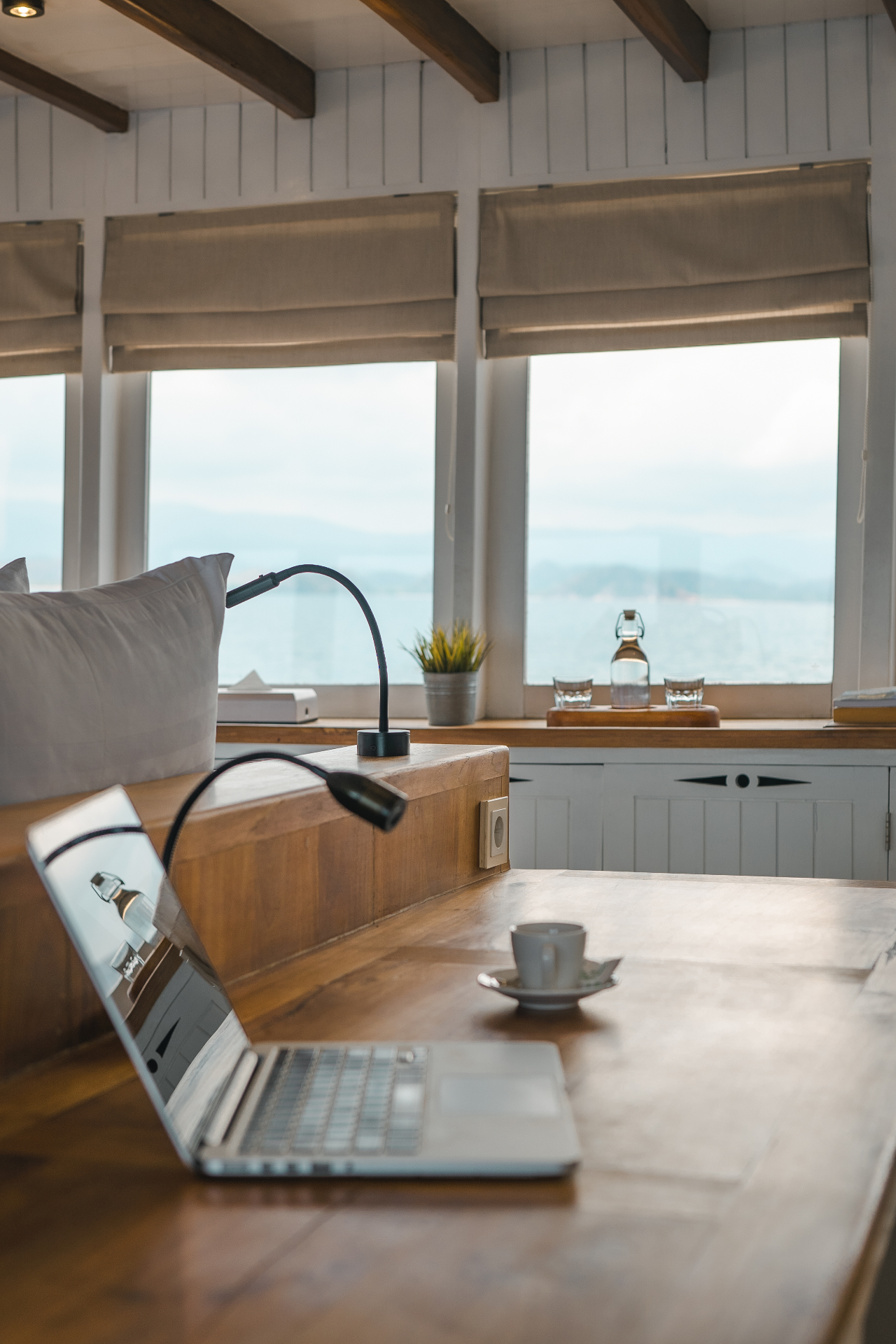 Laptop, espresso and sea views set against Mischief's bright timber interiors and panoramic windows