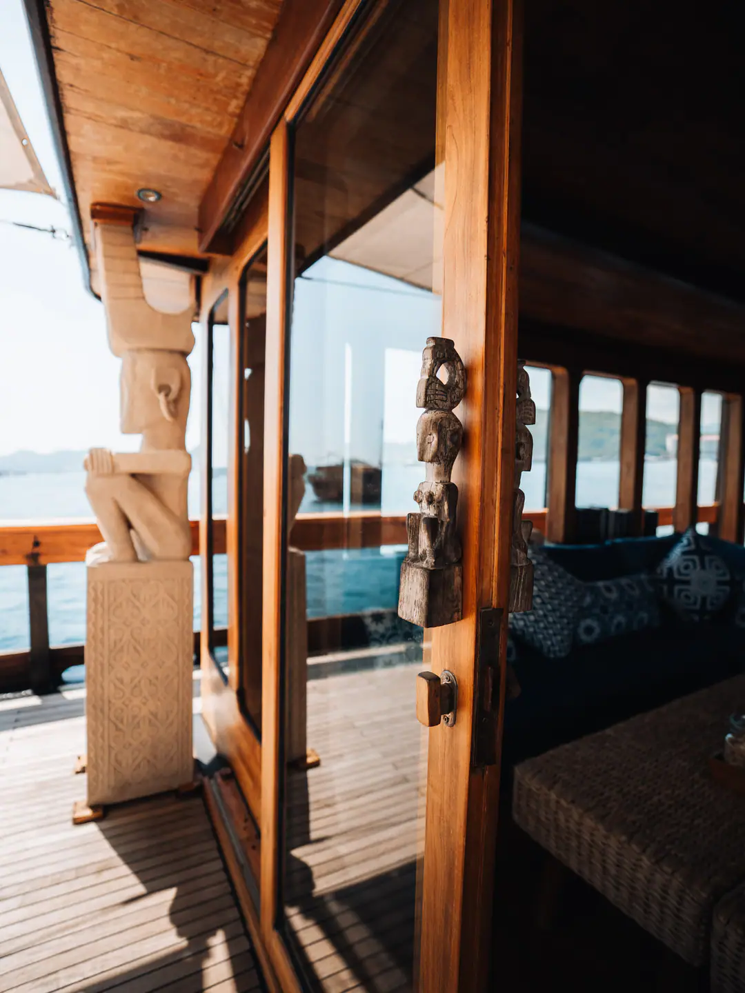 Wooden doorway on The Oracle with tribal carvings leading from the deck to the salon