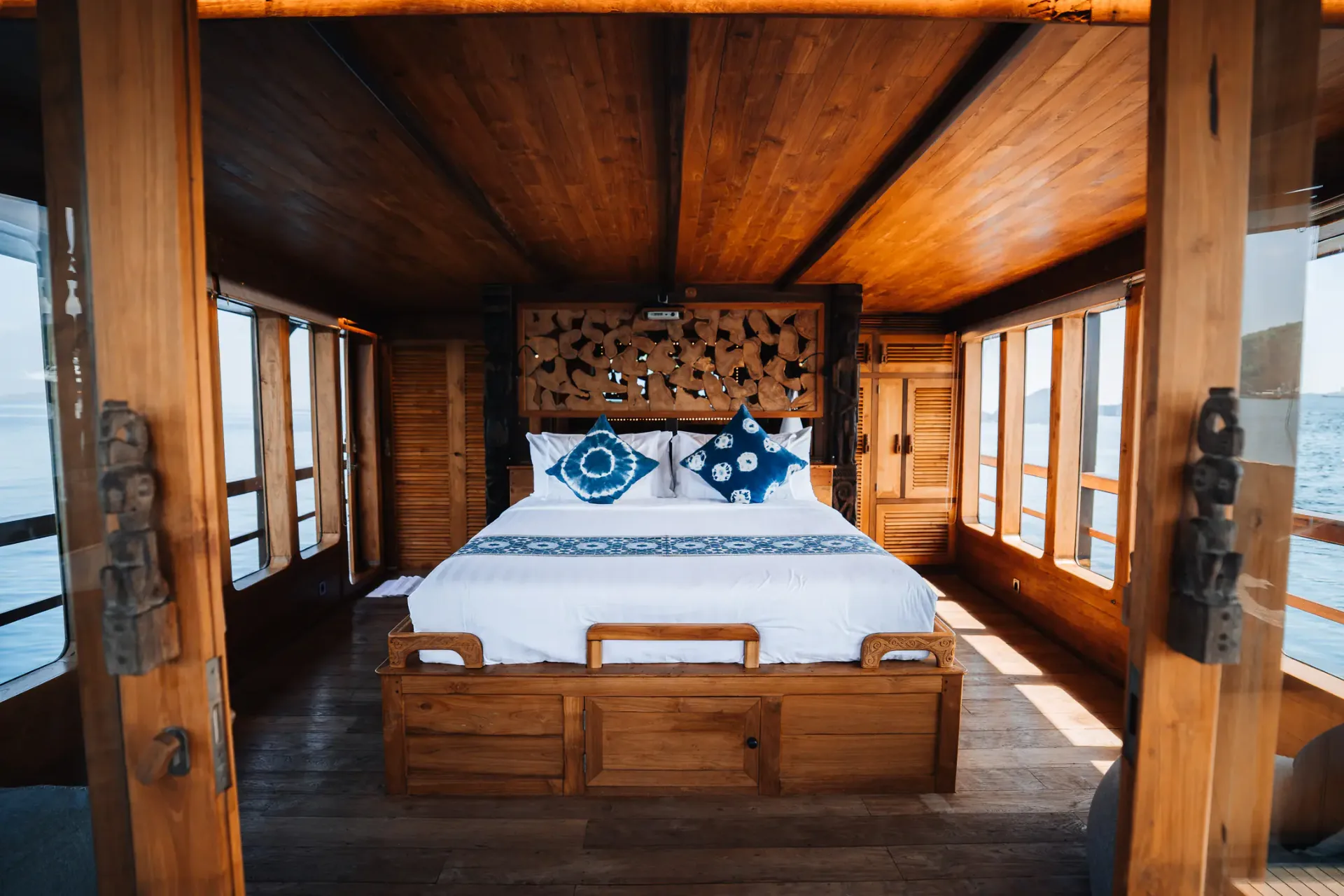 Master cabin on The Oracle with king bed, sculpted headboard and sea-view windows on both sides