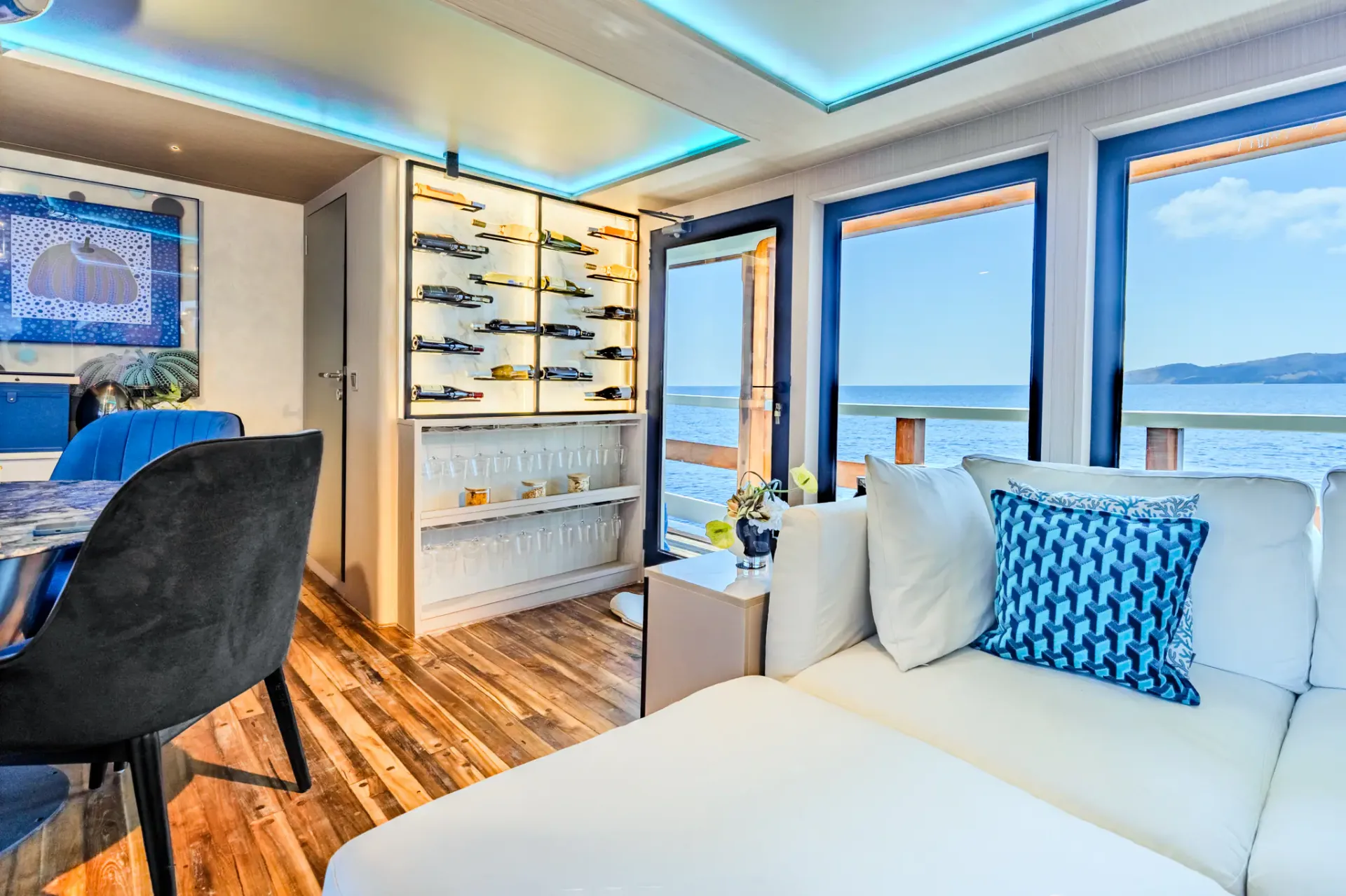 Salon bar corner on Kayra with backlit wine wall and ocean-view sofa